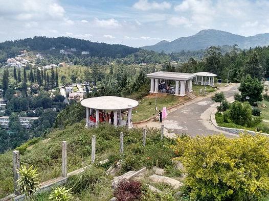 A top-angle shot of Gents Seat in Yercaud featuring white gazebos scattered around with a backdrop of mountains.