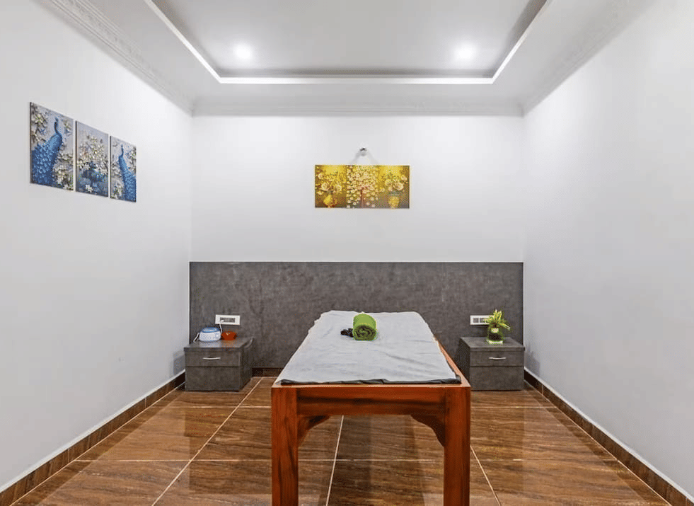 Minimalist spa room with a wooden table and decorative wall art at Siri Ambari Resorts and Spa.