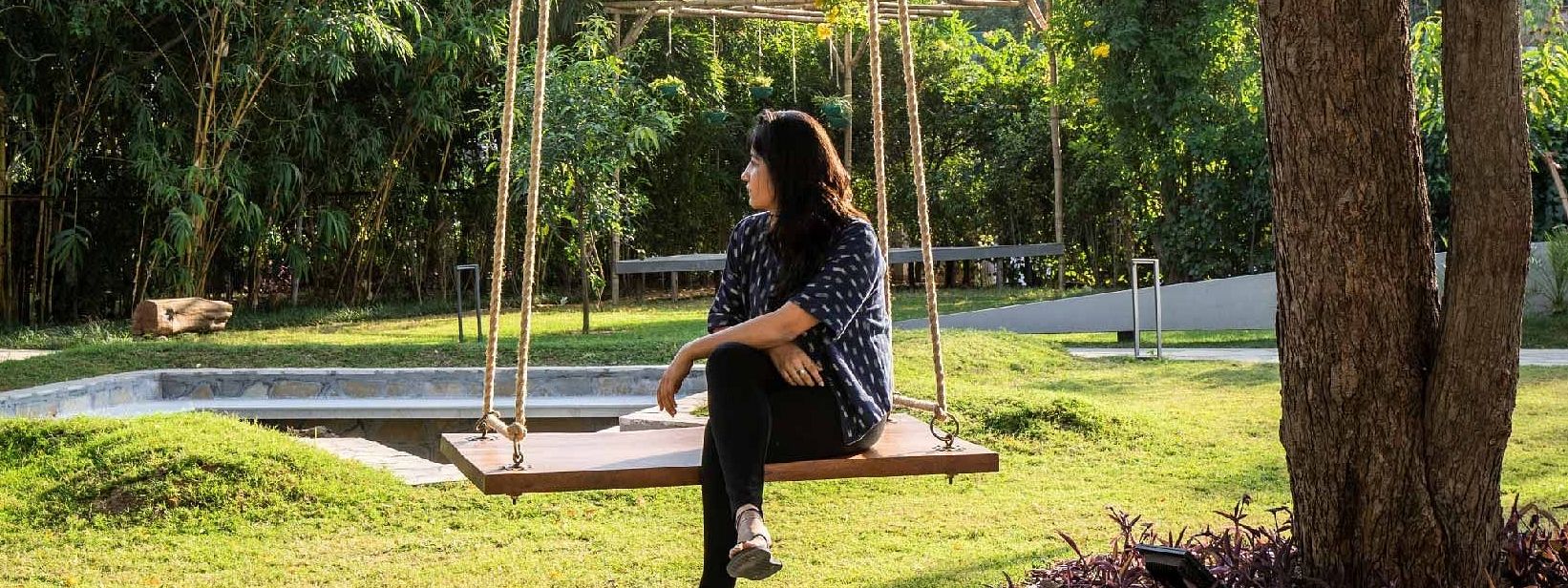 Guest sitting on a swing under a tree in the garden area at Karma Chalets.