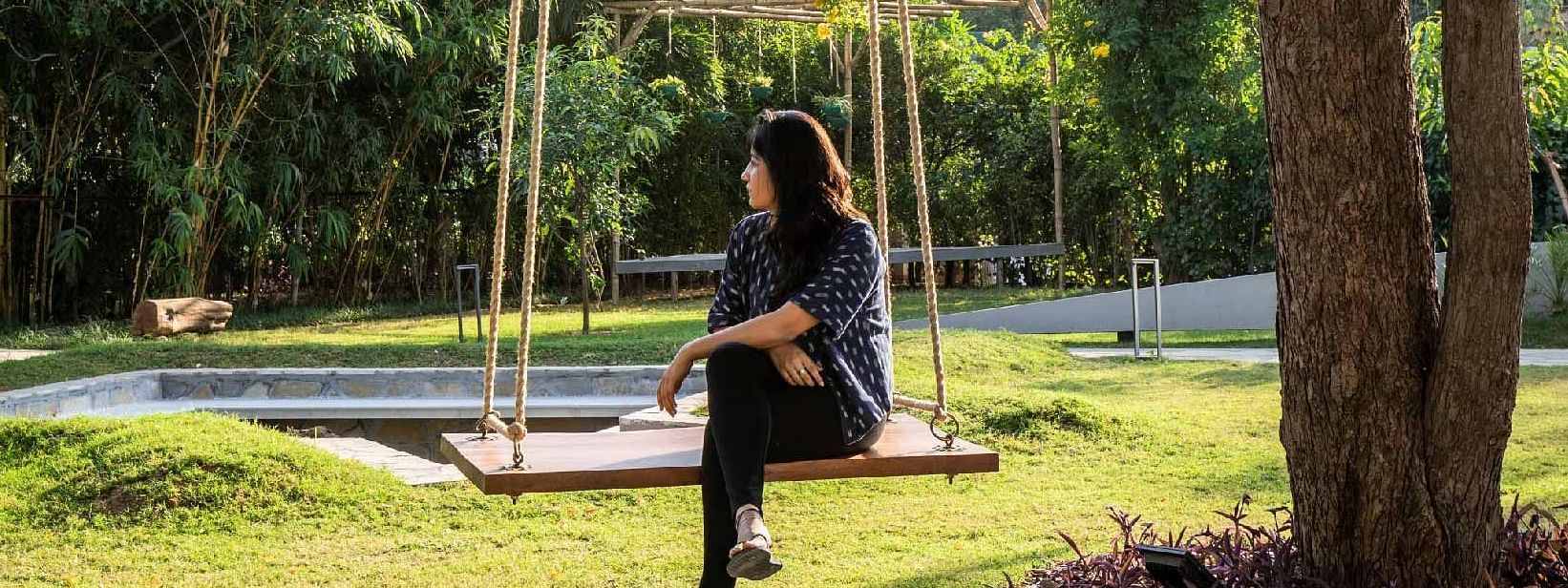 Guest sitting on a swing under a tree in the garden area at Karma Chalets.