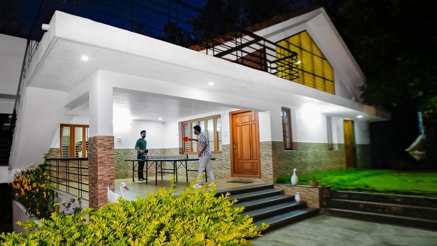 Facade view of WOW Bungalow, Yercaud, with two people playing table tennis on the porch.