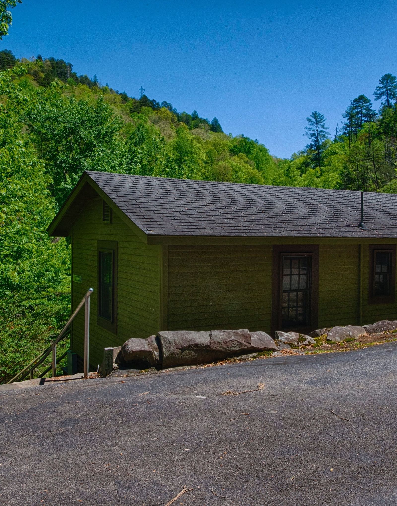 the Overlook cabin with green exterior walls and dark grey room with lush green hills in the background - Historic Tapoco Lodge