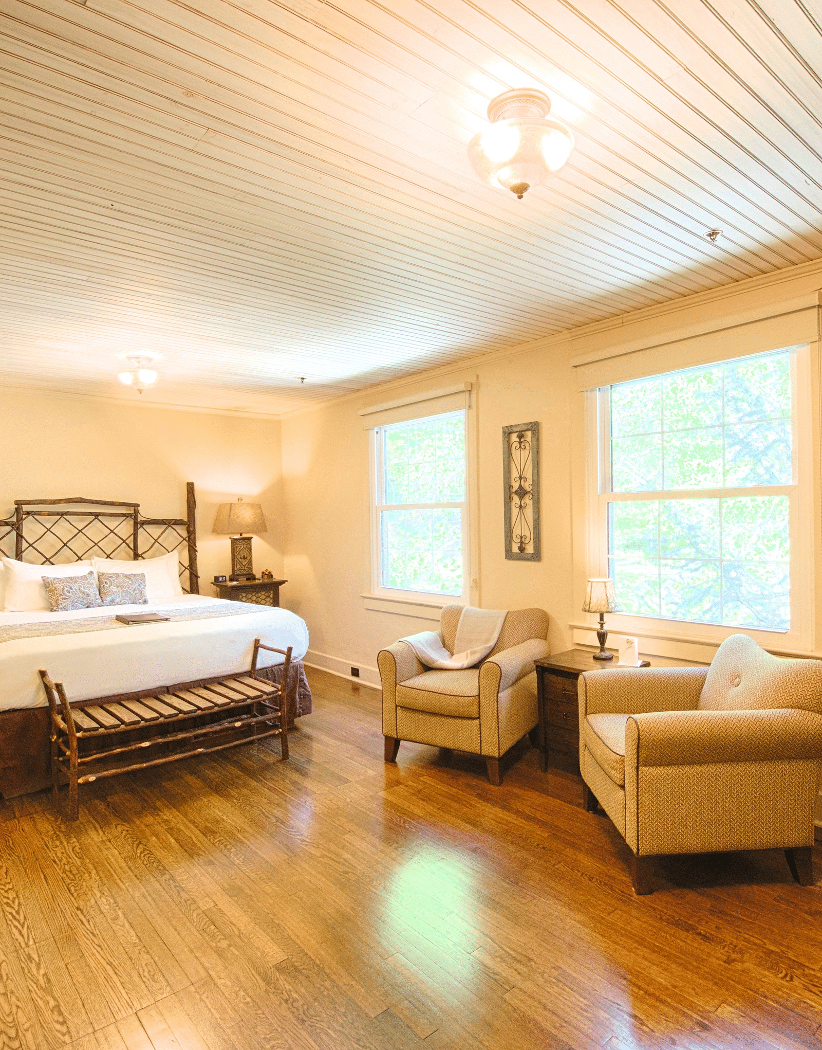 corner view image of a spacious bedroom featuring a common seating area along with a comfortable double bed - Historic Tapoco Lodge