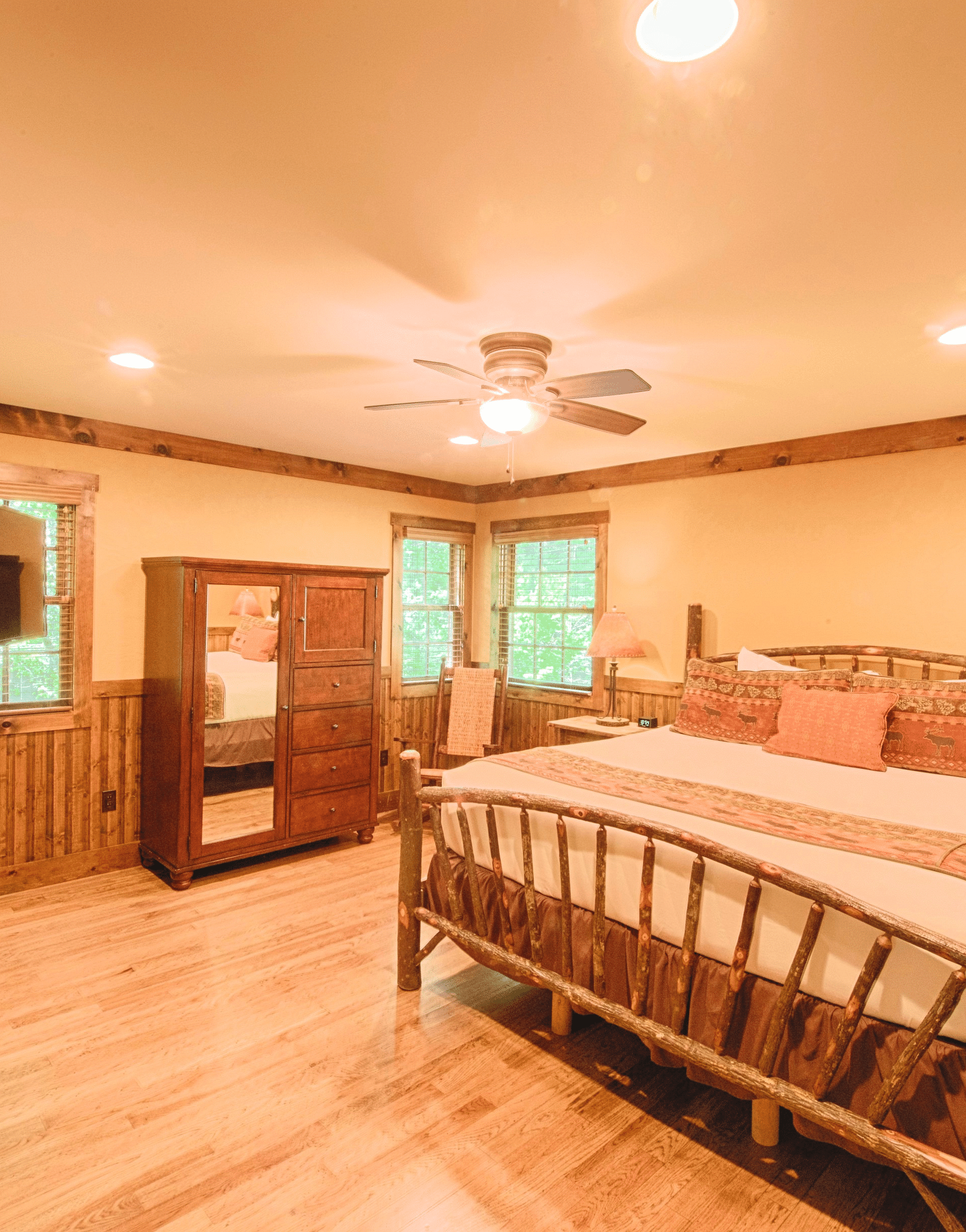 a brightly lit bedroom with a featuring a double bed along with a wooden wardrobe in the corner - Historic Tapoco Lodge