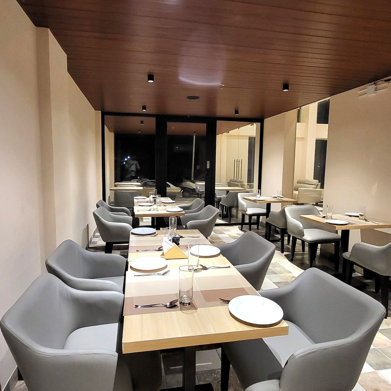 Grey chairs and tables set in a row in 6ix Sea View Restaurant at 6ix Seashore Hotel, Port Blair
