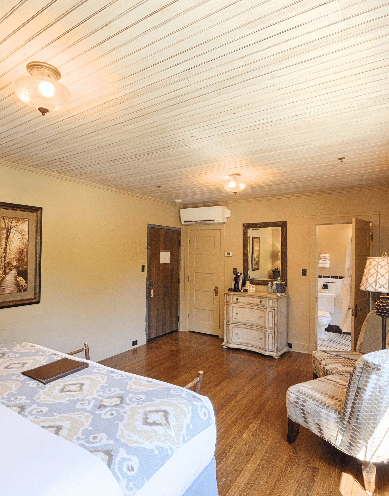 corner view of a cozy bedroom featuring a comfortable double bed with two decorative wall mounted frames - Historic Tapoco Lodge