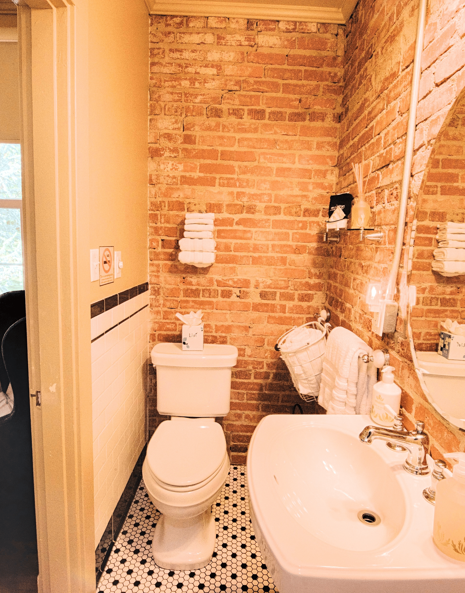 a cozy bathroom with huge curcular mirror above the wash basin and a commode in the corner - Historic Tapoco Lodge