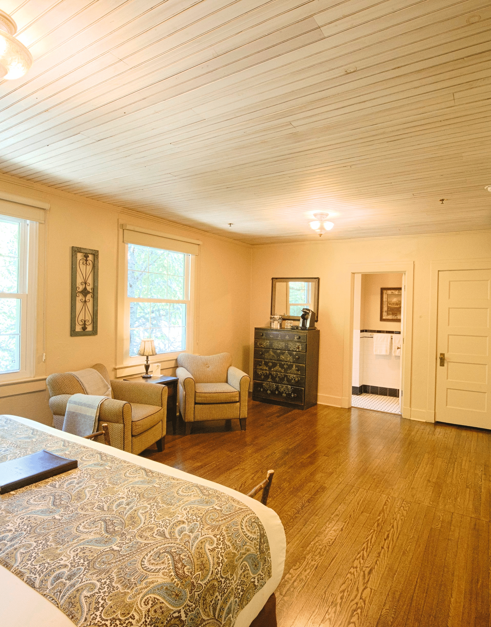 a brightly lit bedroom featuring a double bed with a file kept over it and with a comfortable seating area in front of it - Historic Tapoco Lodge