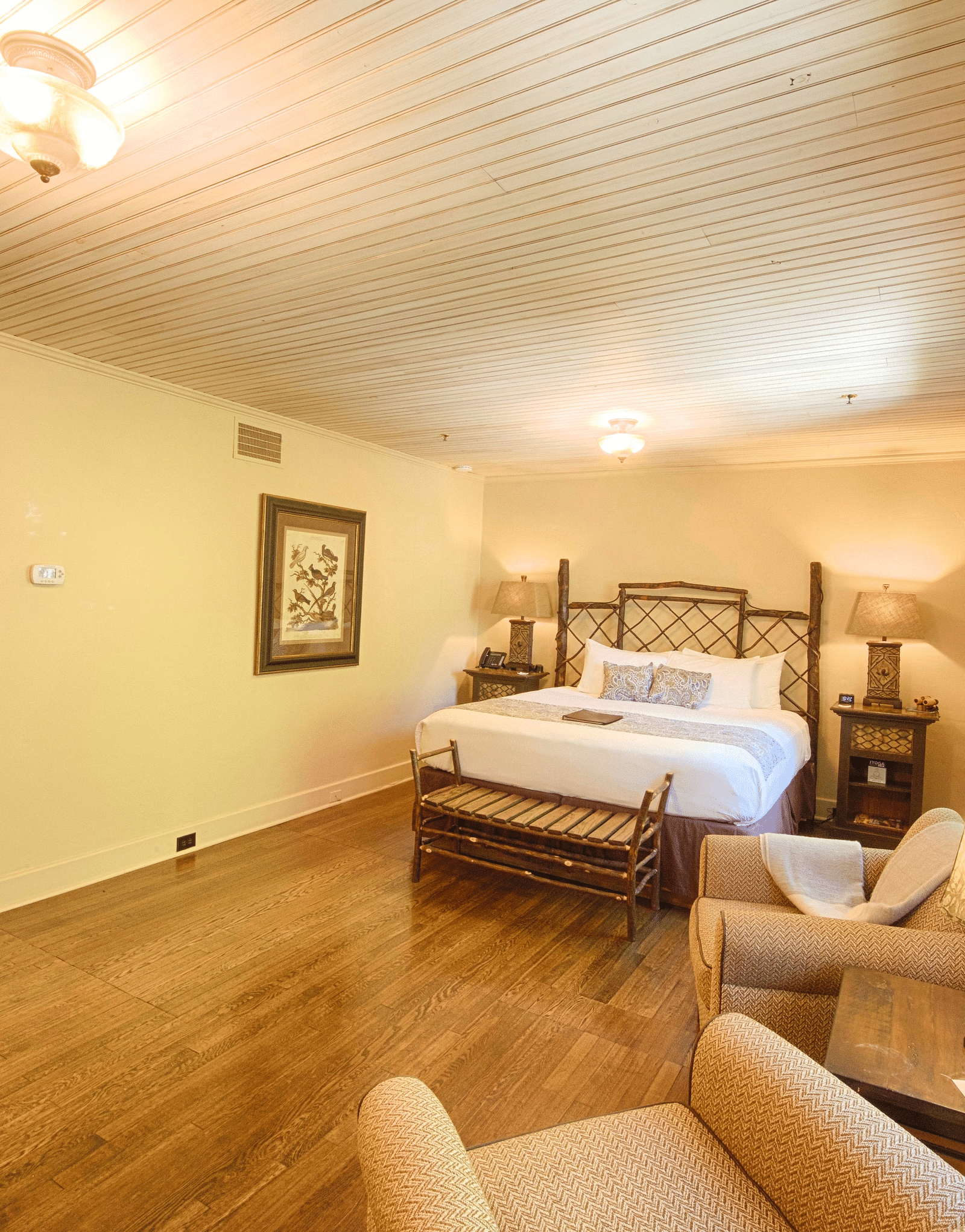 dull view image of a bedroom with a wooden door featuring a plush double bed with two bed side tables on either side of it - Historic Tapoco Lodge