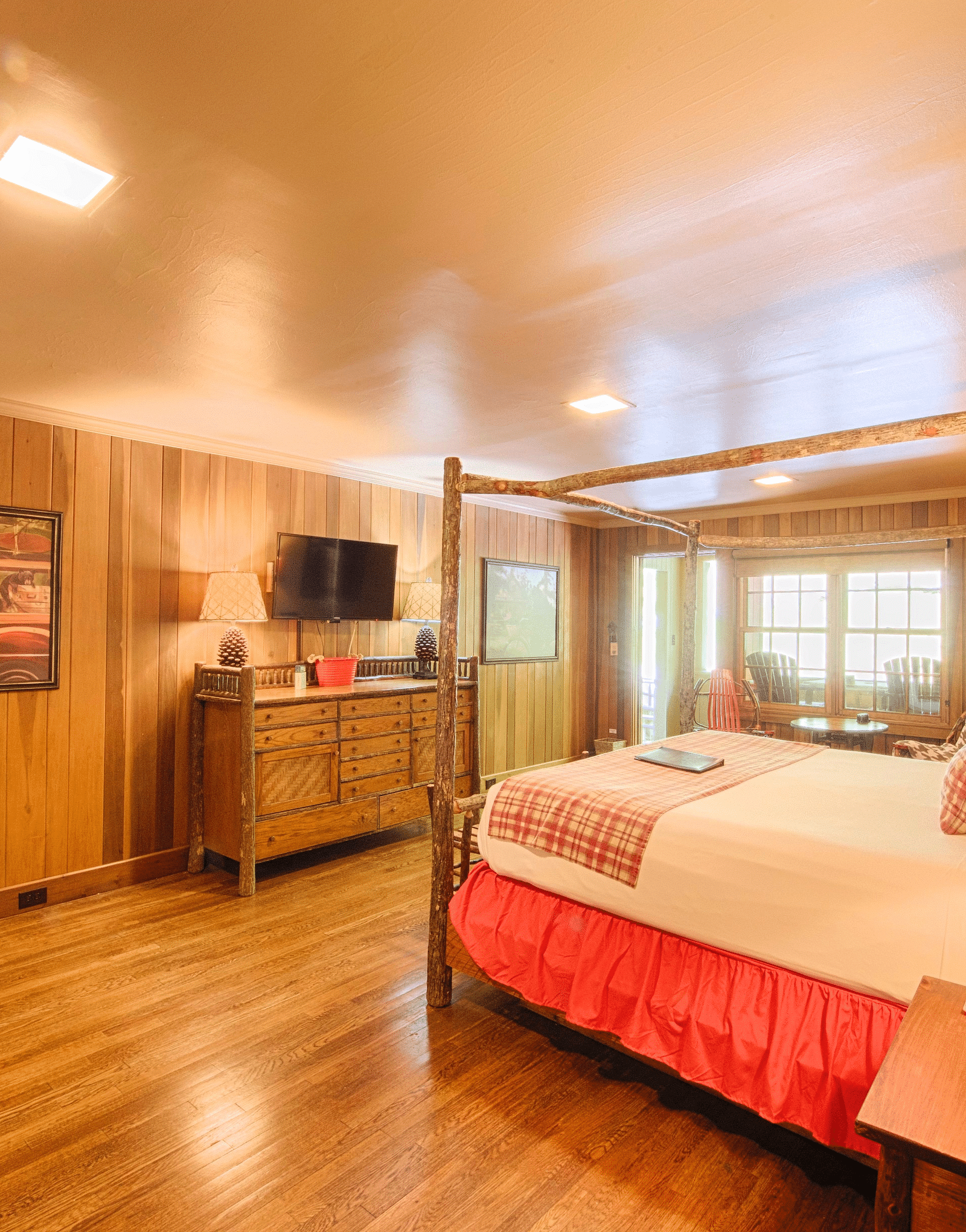 a double bed with a lamp kept on side table placed opposite to a wall mounted television in a room with wooden interiors - Historic Tapoco Lodge