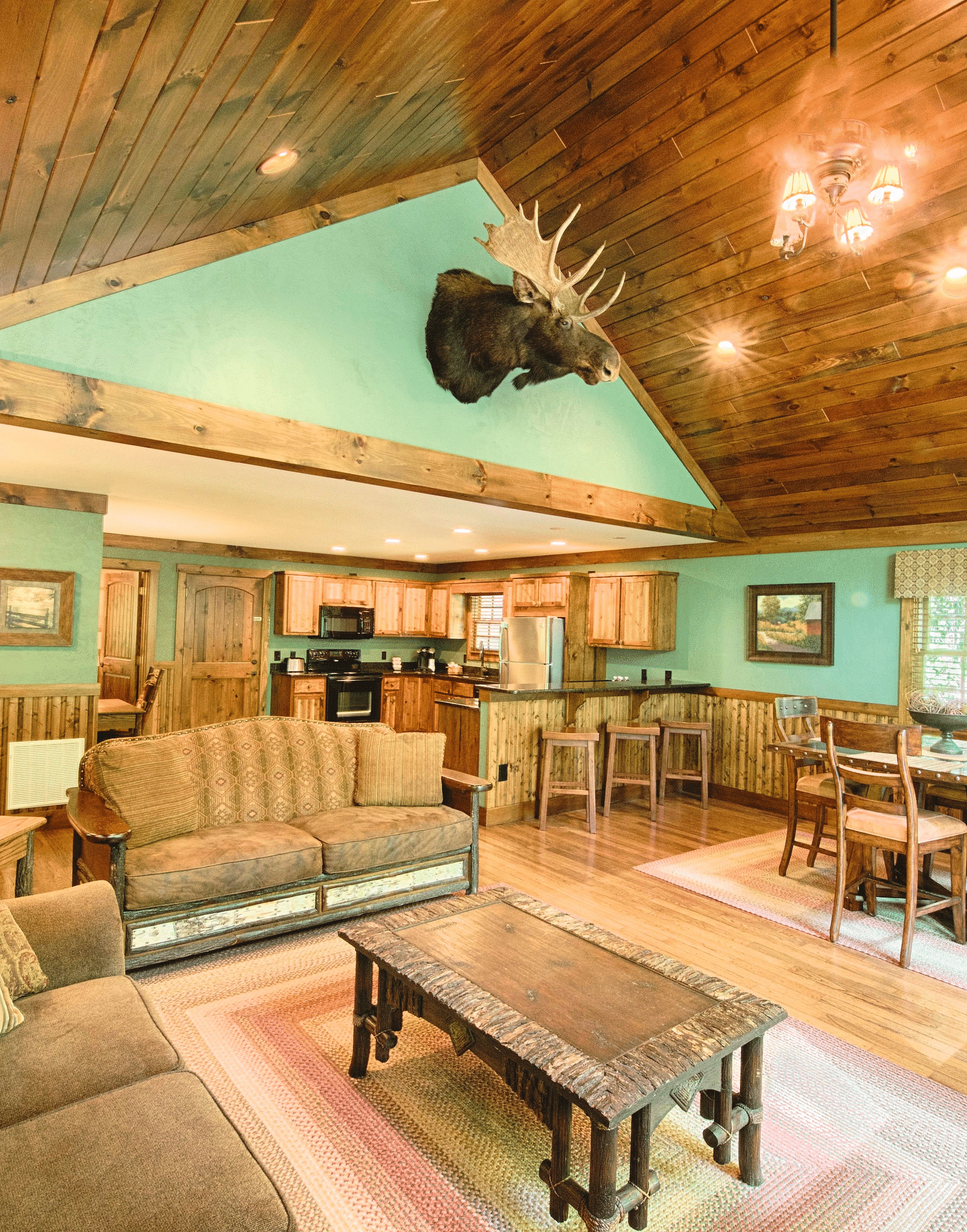 full view image of the living area with pastel green colored walls complemented by a decorative stag head - Historic Tapoco Lodge