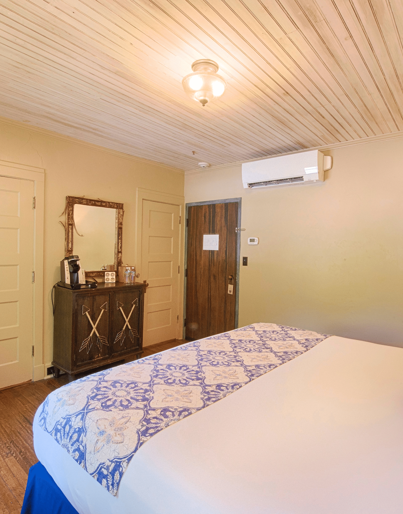 side view of a bedroom featuring a double bed along with a blue coloured arm chair and a wall mounted split air-conditioner - Historic Tapoco Lodge