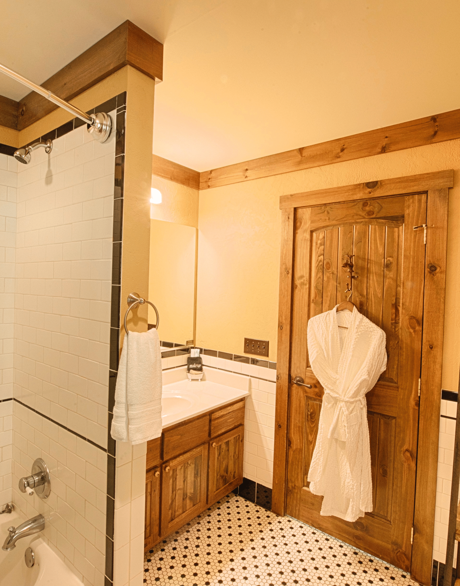 a bathroom featuring a storage shelf with fresh linens and a wooden door with a bathrobe hanging on it - Historic Tapoco Lodge