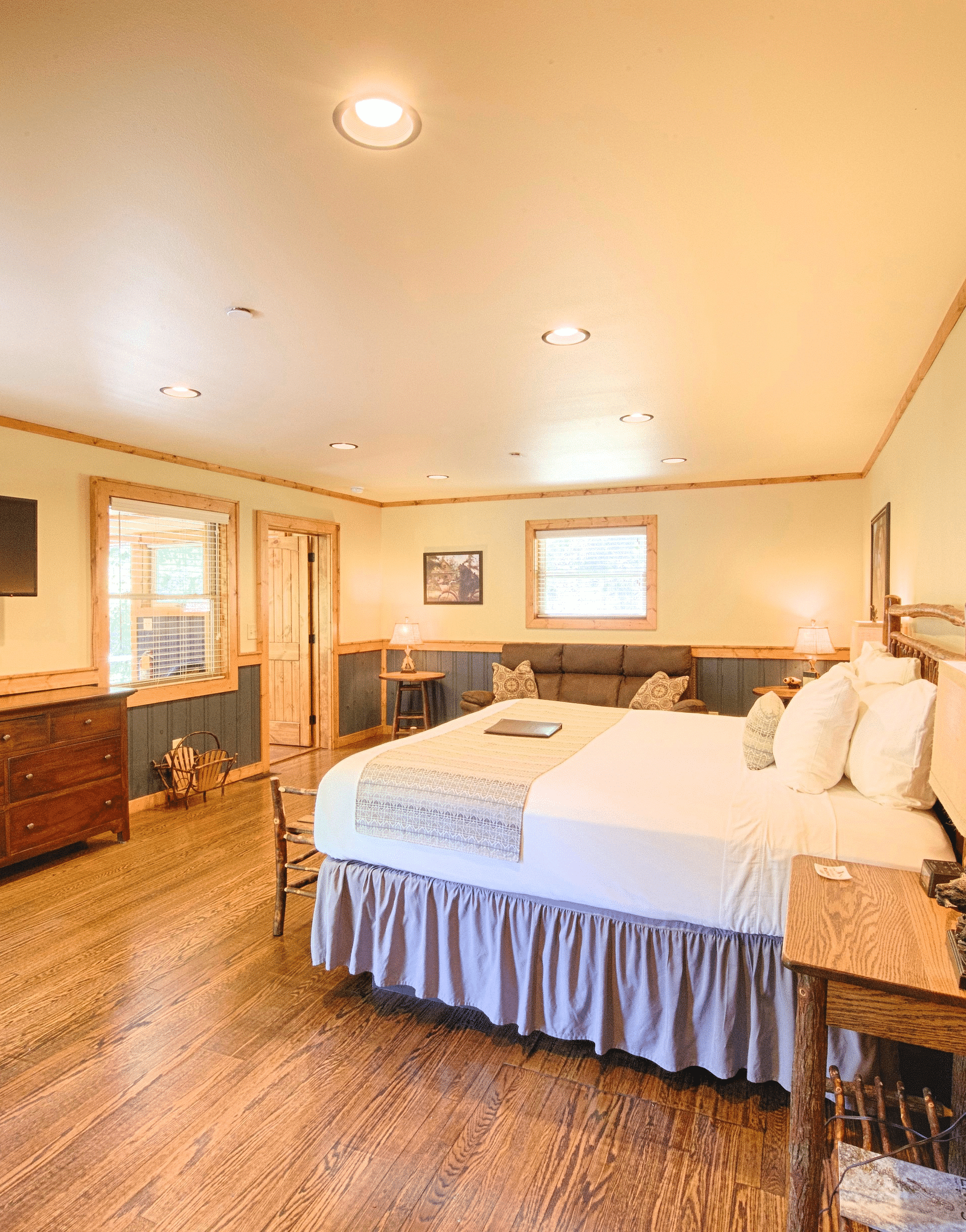 a beautiful room with a flat screen television and a wooden shelf placed opposite to a double bed - Historic Tapoco Lodge