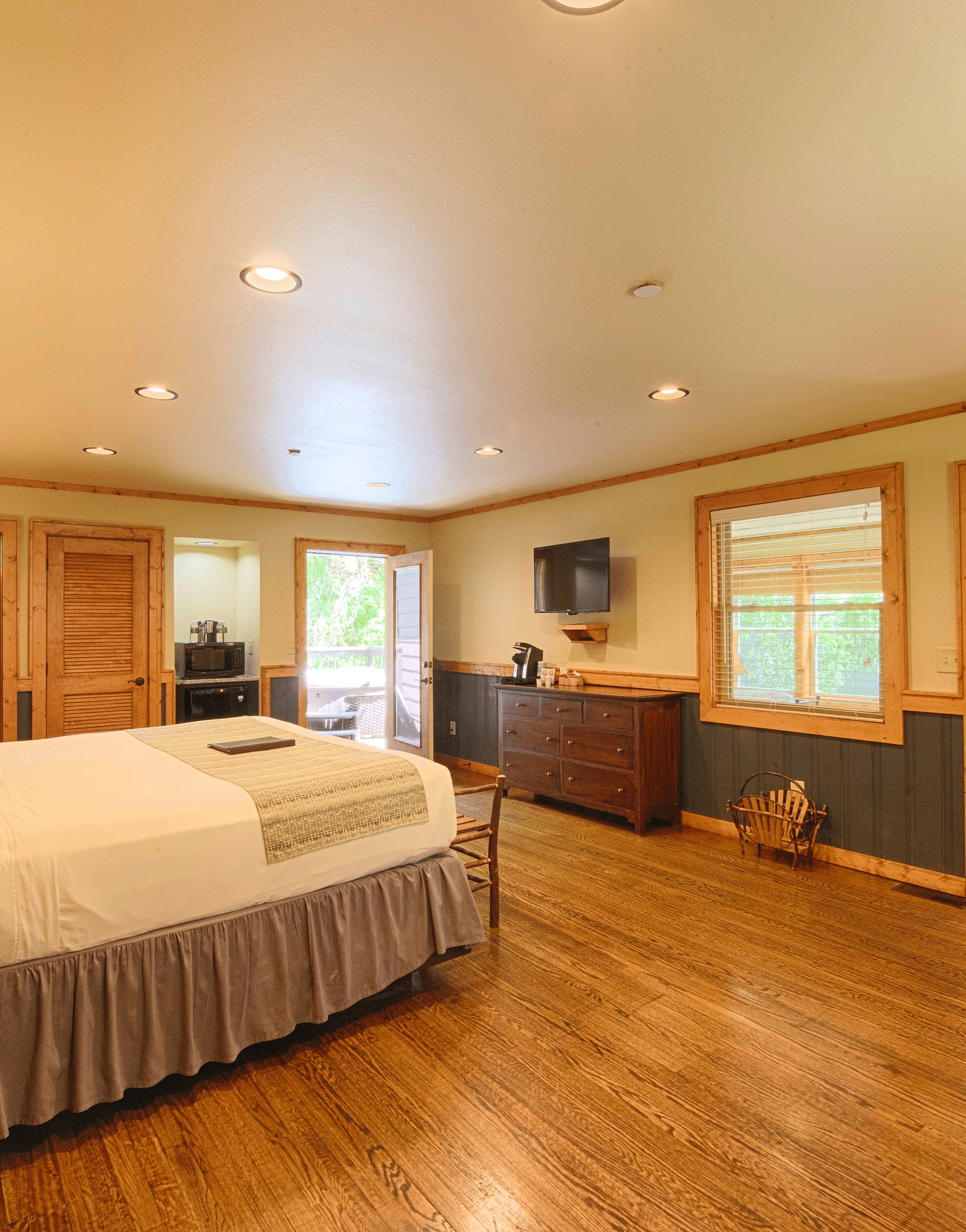 corner view of a spacious bedroom that includes a double bed with a bedside table besides it and a door frame going to the other room - Historic Tapoco Lodge