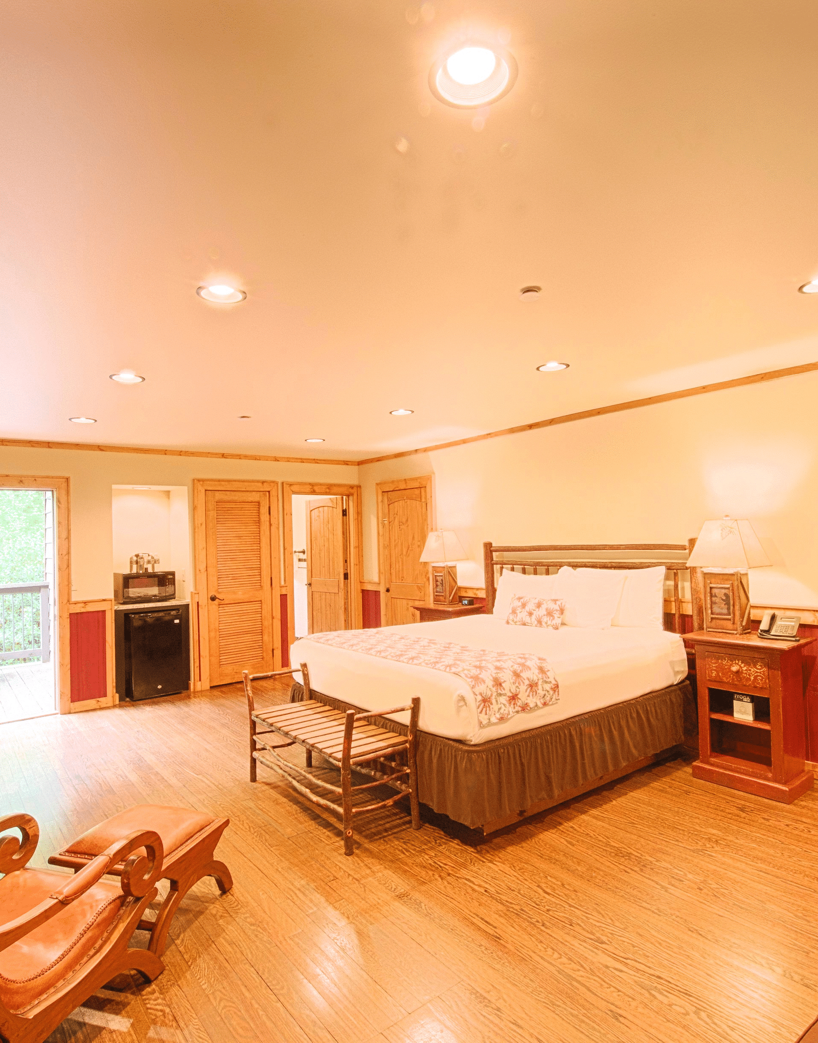 a beautiful room featuring a double bed with a seating area and a cushioned arm chair in the side  - Historic Tapoco Lodge