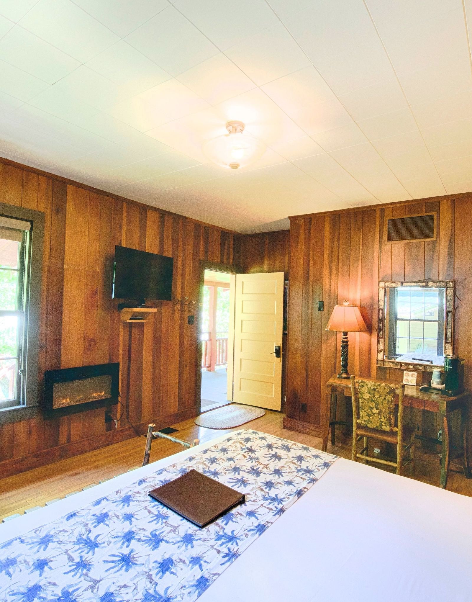 a cozy room featuring wooden interiors overlooking a double bed, a writing desk along with a vintage inspired decor - Historic Tapoco Lodge
