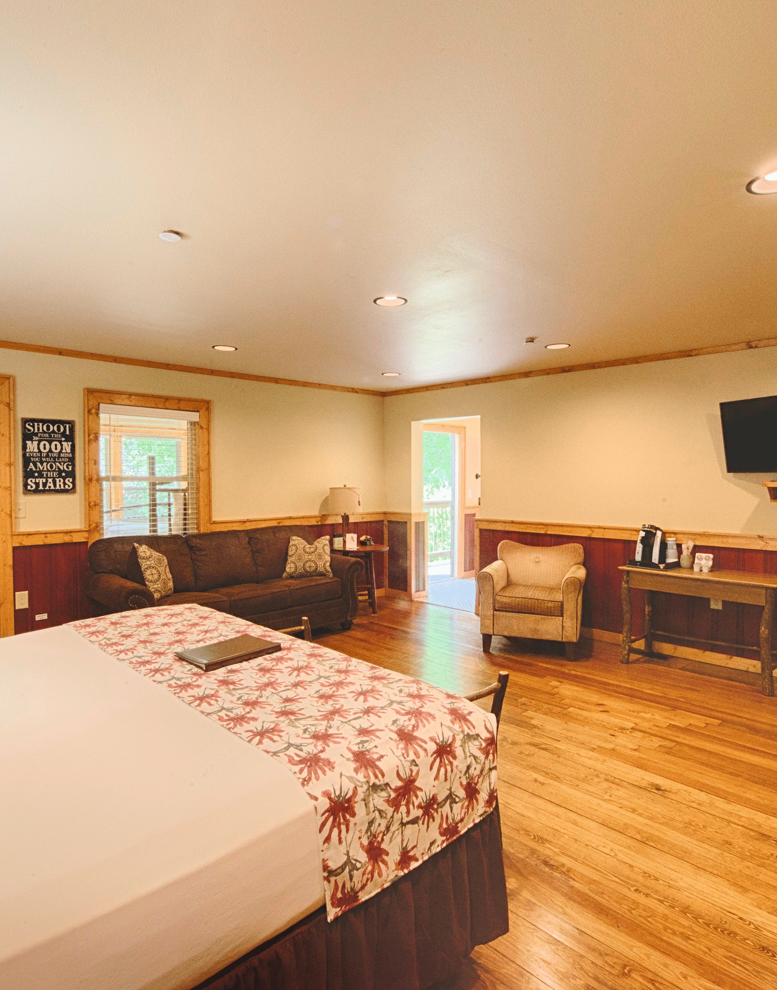 a spacious room with a double bed along with comfortable armchairs kept under a wall mounted television - Historic Tapoco Lodge