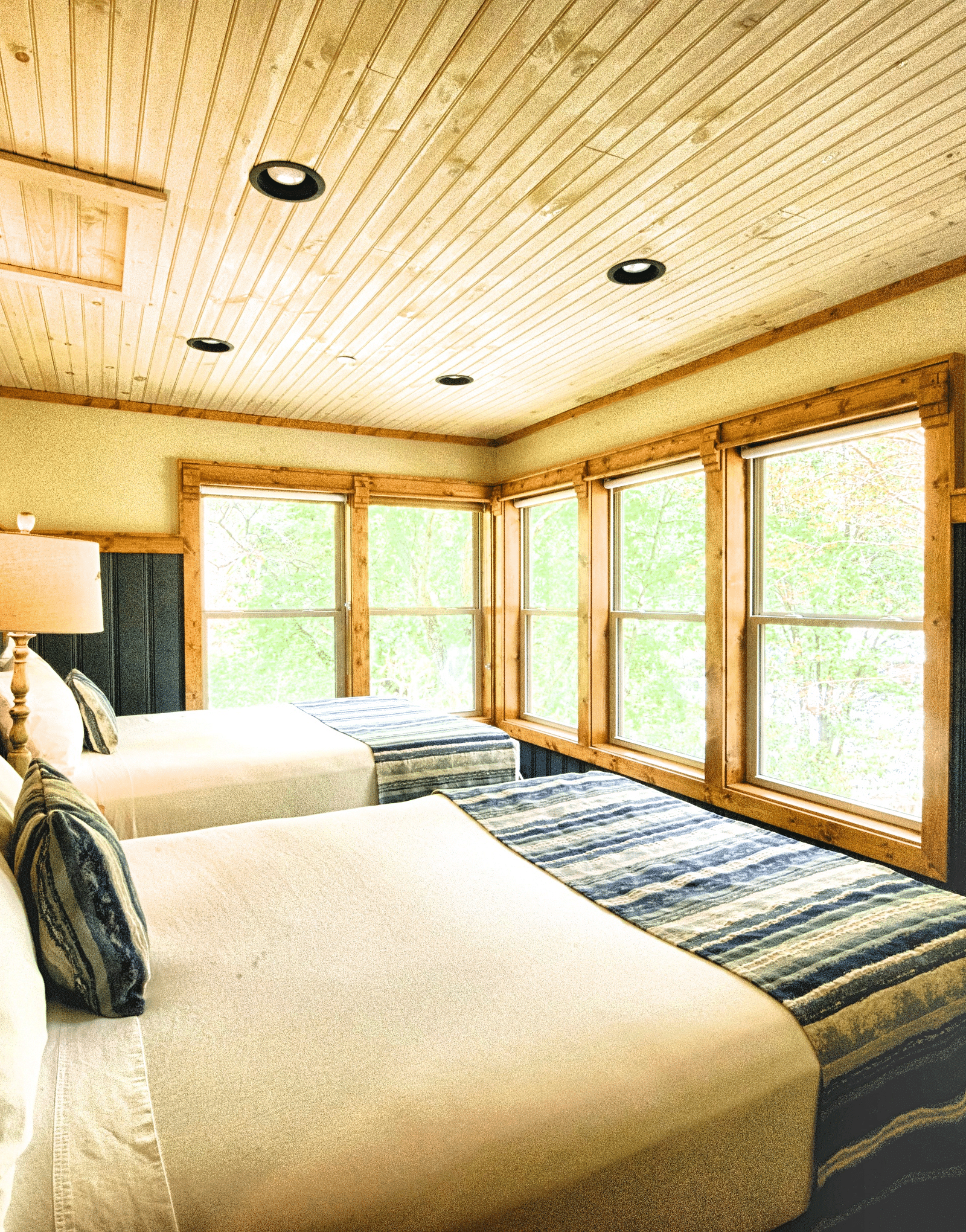 a cozy bedroom with two beds and a wooden ceiling along with huge five panel window - Historic Tapoco Lodge