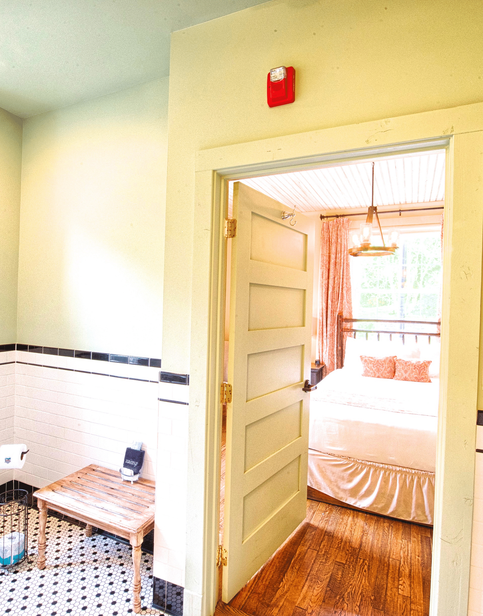 a brightly lit bathroom featuring a door opening to the bedroom overlooking the double bed - Historic Tapoco Lodge