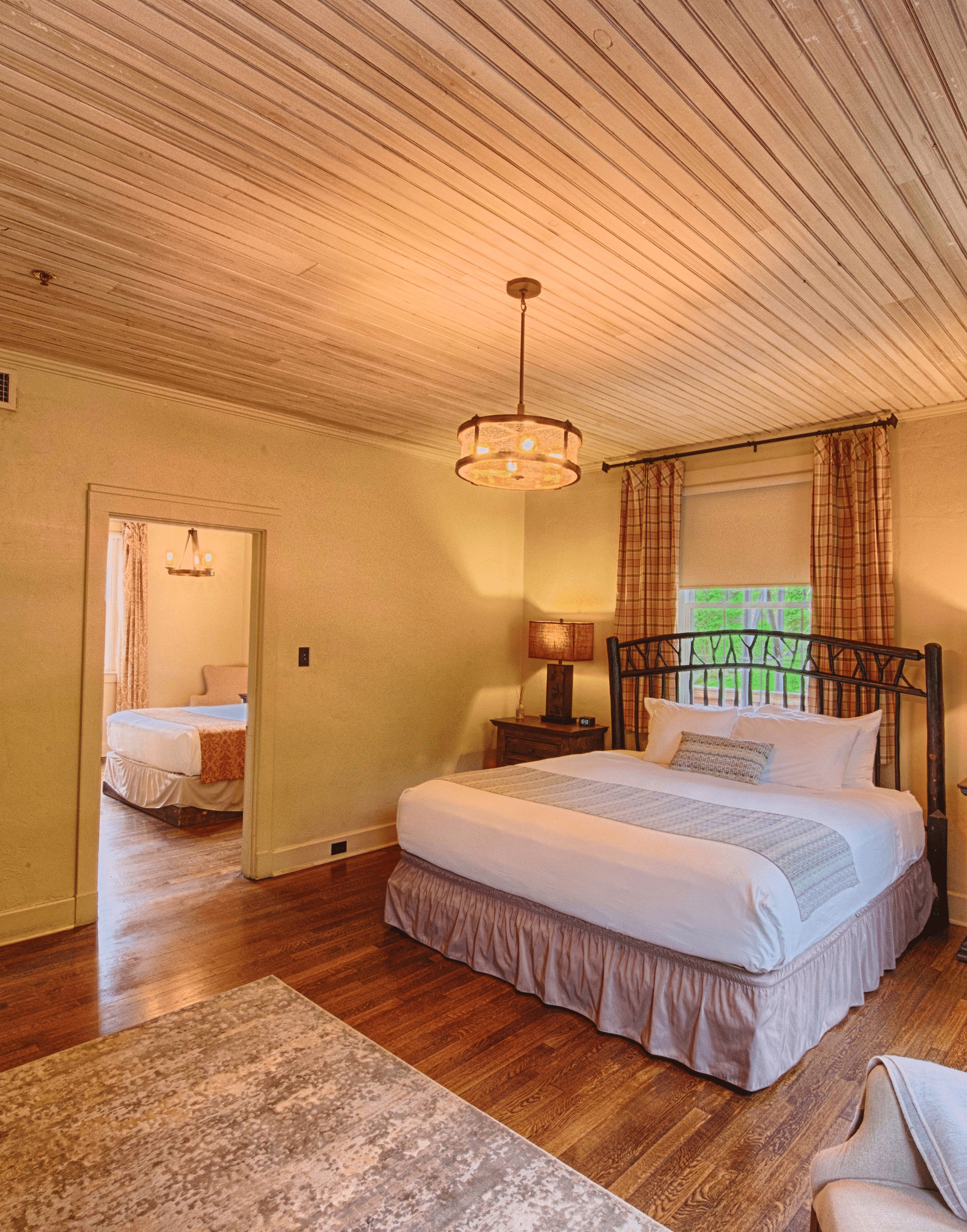 full view image of the evergreen suite featuring a double bed and a small window behind it - Historic Tapoco Lodge