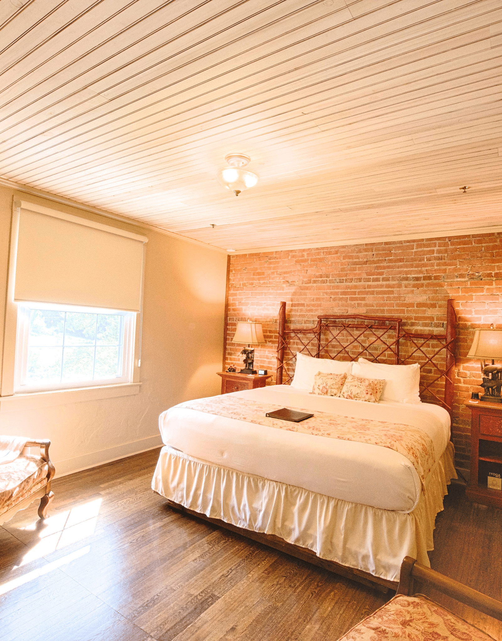 full view image of a bedroom featuring a bricked wall behind the double bed - Historic Tapoco Lodge
