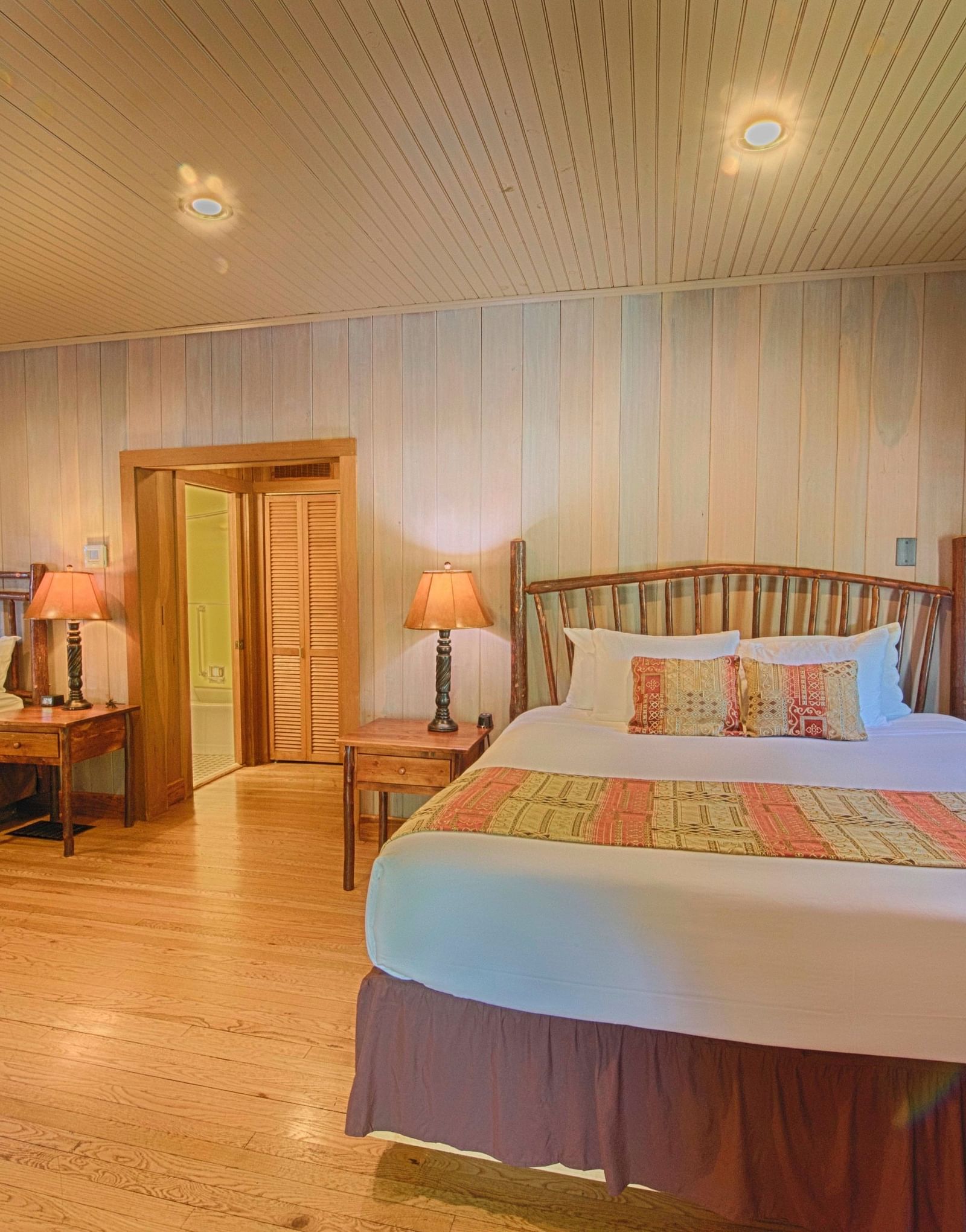 front view image of a double bed in a bedroom with two bed side tables on the either side of it - Historic Tapoco Lodge