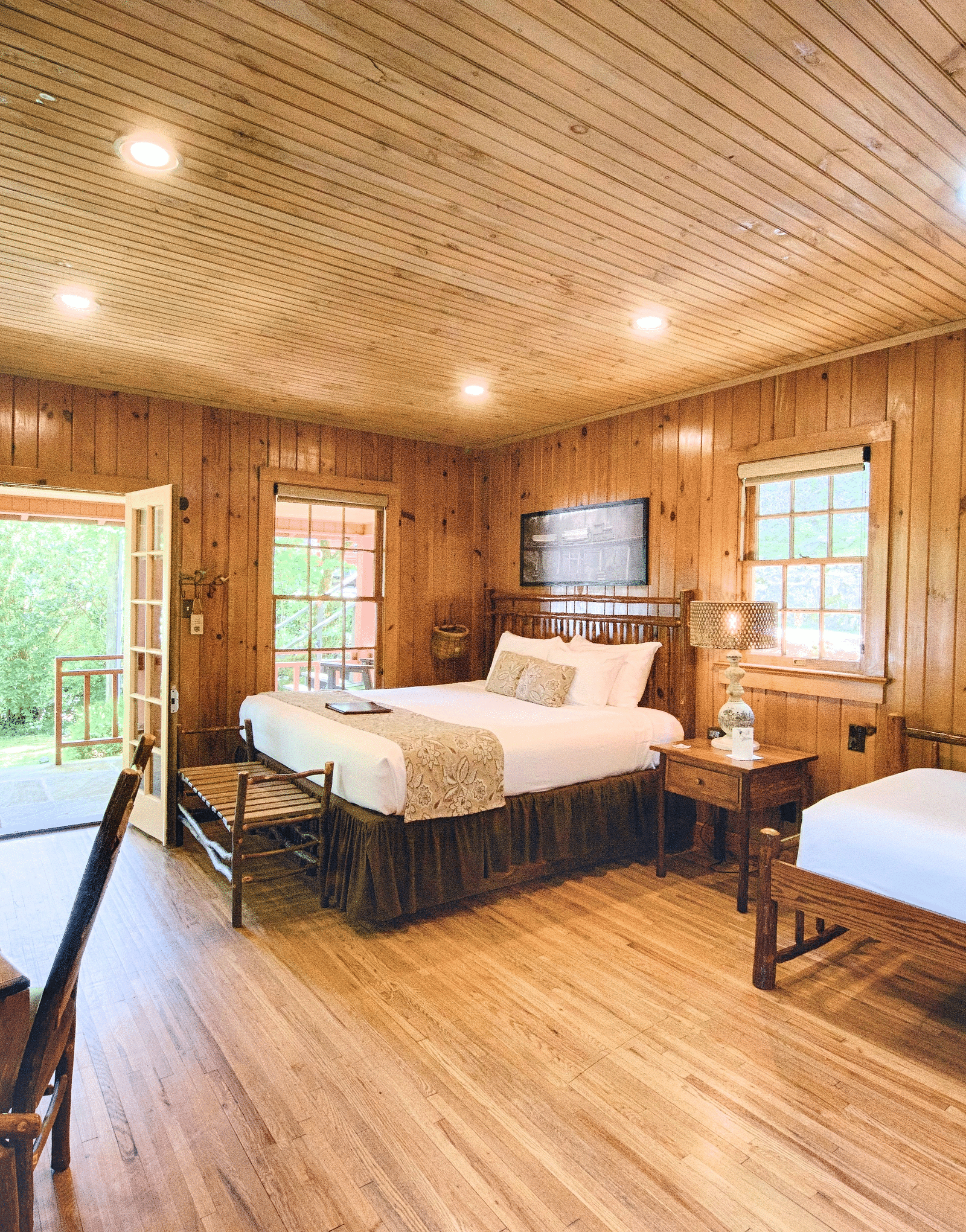 a room featuring a huge entrance to the room with wooden interiors featuring a double bed and a work desk and chair - Historic Tapoco Lodge