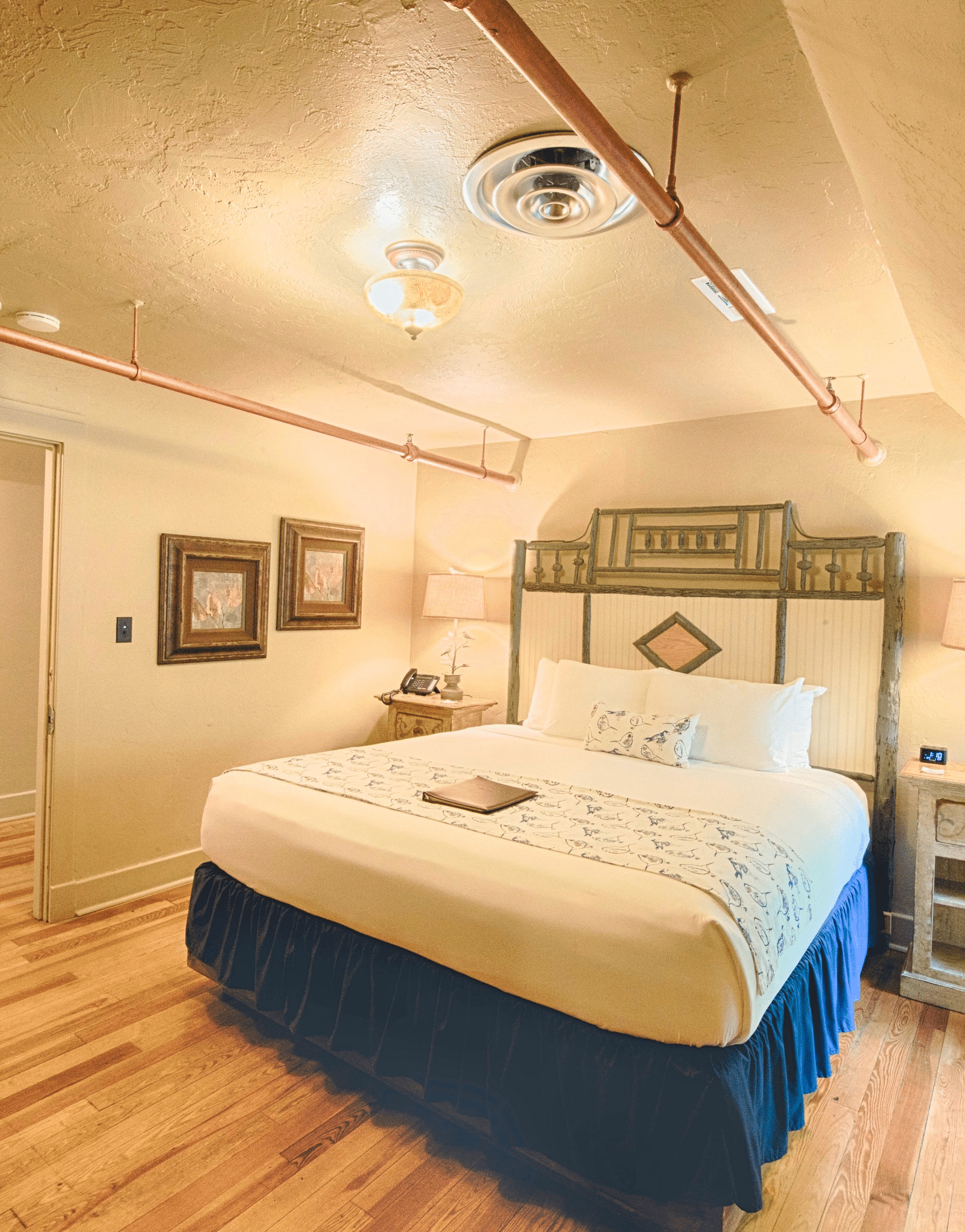 full view image of the bedroom of rhododendron suite featuring a huge double bed with bedside table beside it - Historic Tapoco Lodge