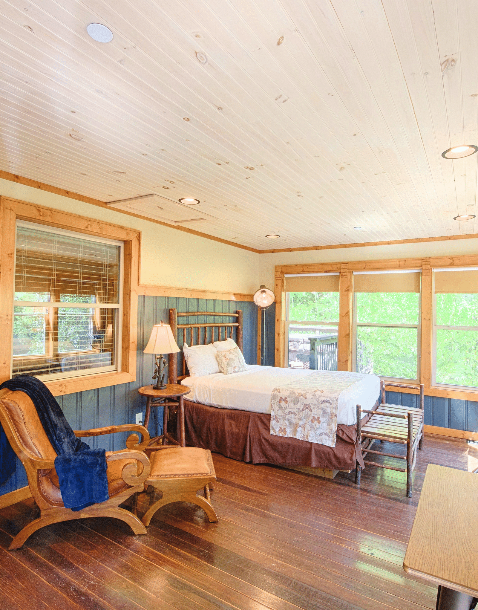 a brightly lit room with ample natural light featuring blue colored wooden panels on the wall and a double bed - Historic Tapoco Lodge