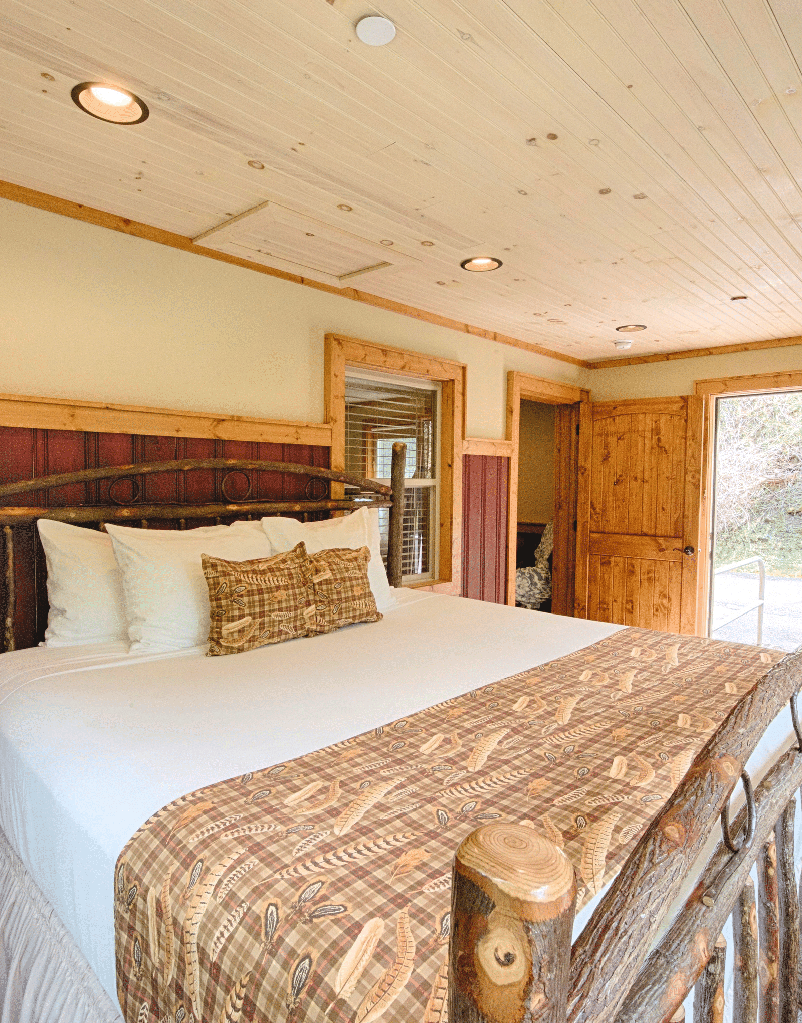 close up image of a plush double bed with a door opening to the exterior of the room - Historic Tapoco Lodge