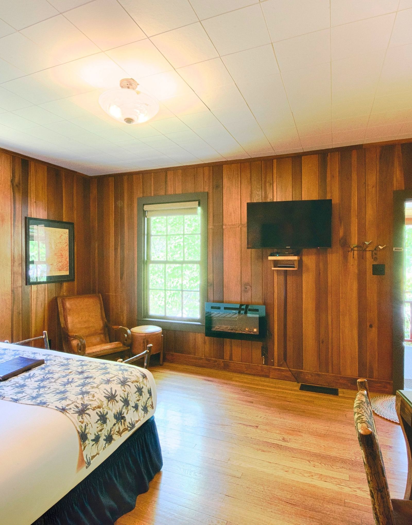 a spacious room adorned with wooden walls, a double bed and a wall mounted flat screen television - Historic Tapoco Lodge