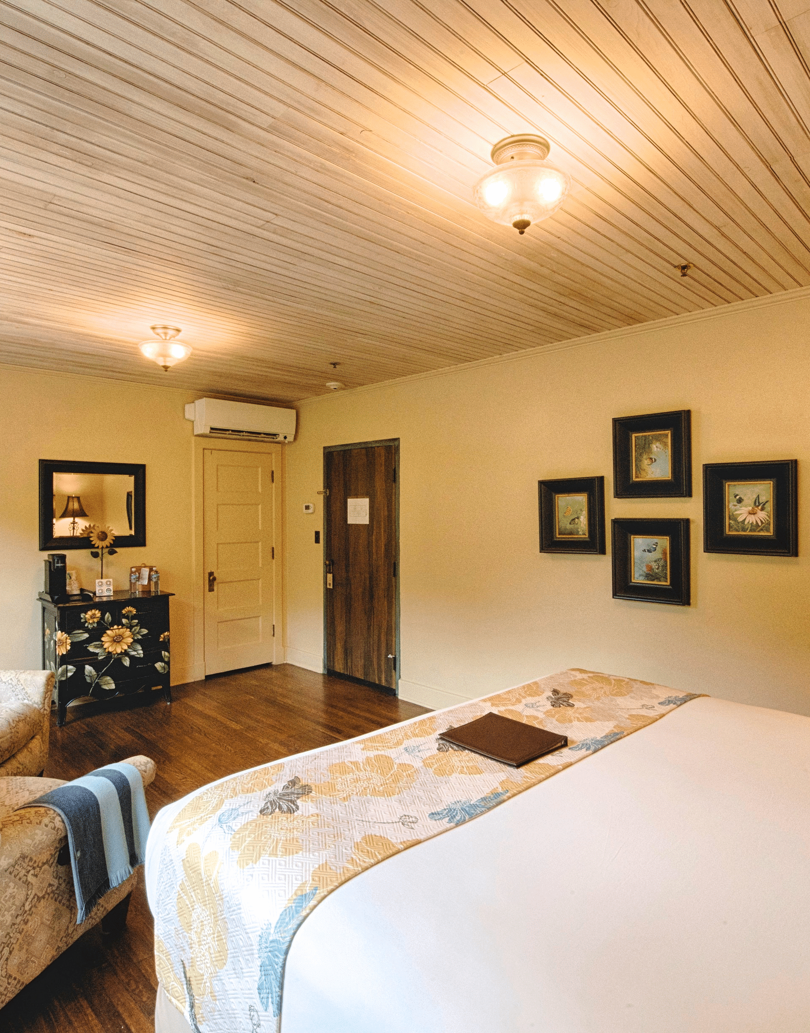 a cozy bedroom with minimalist and sleek interiors featuring a double bed and the back of a cushioned armchair - Historic Tapoco Lodge
