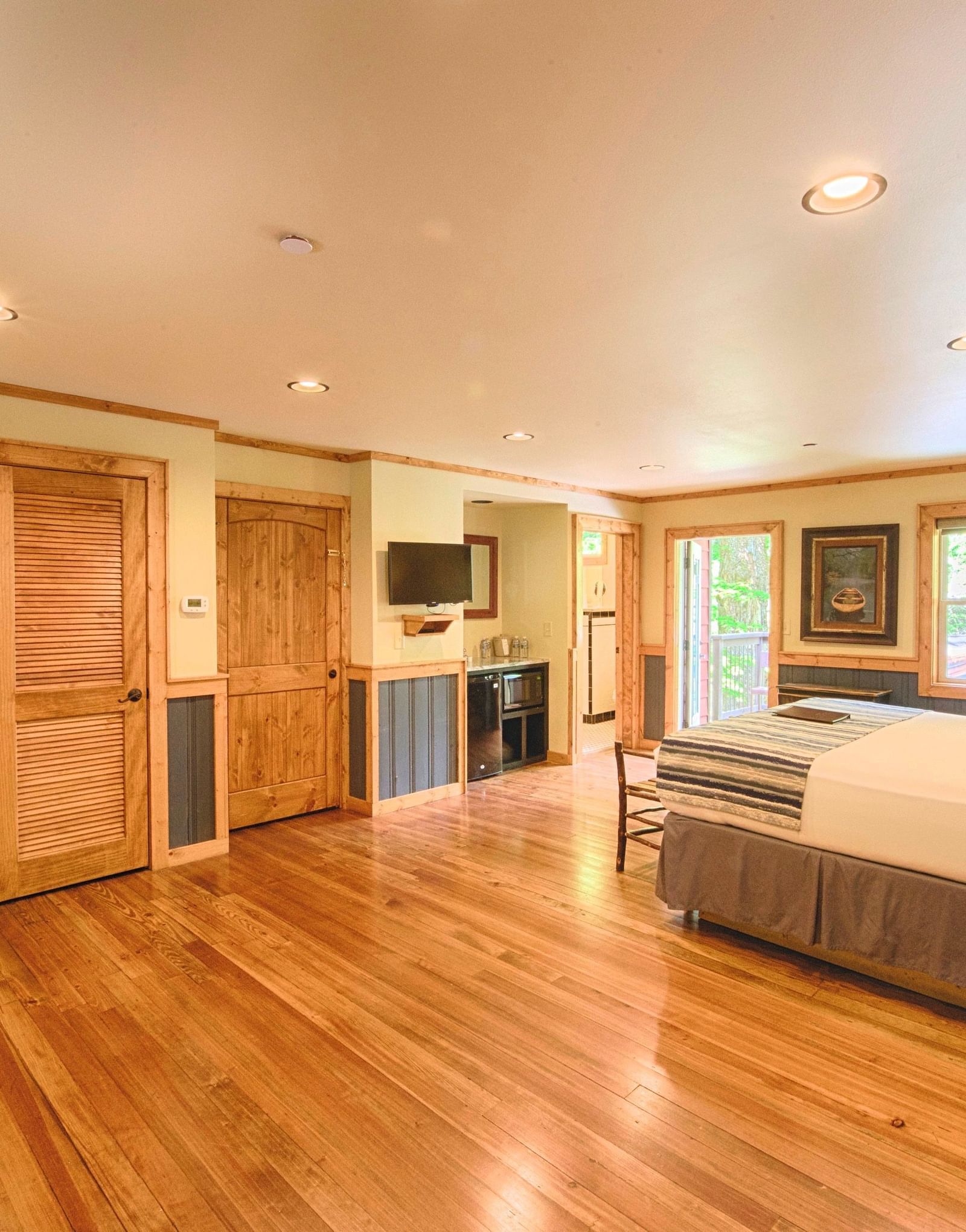 a bedroom with a double bed and a common seating area in the corner with two wooden doors right in front of it - Historic Tapoco Lodge