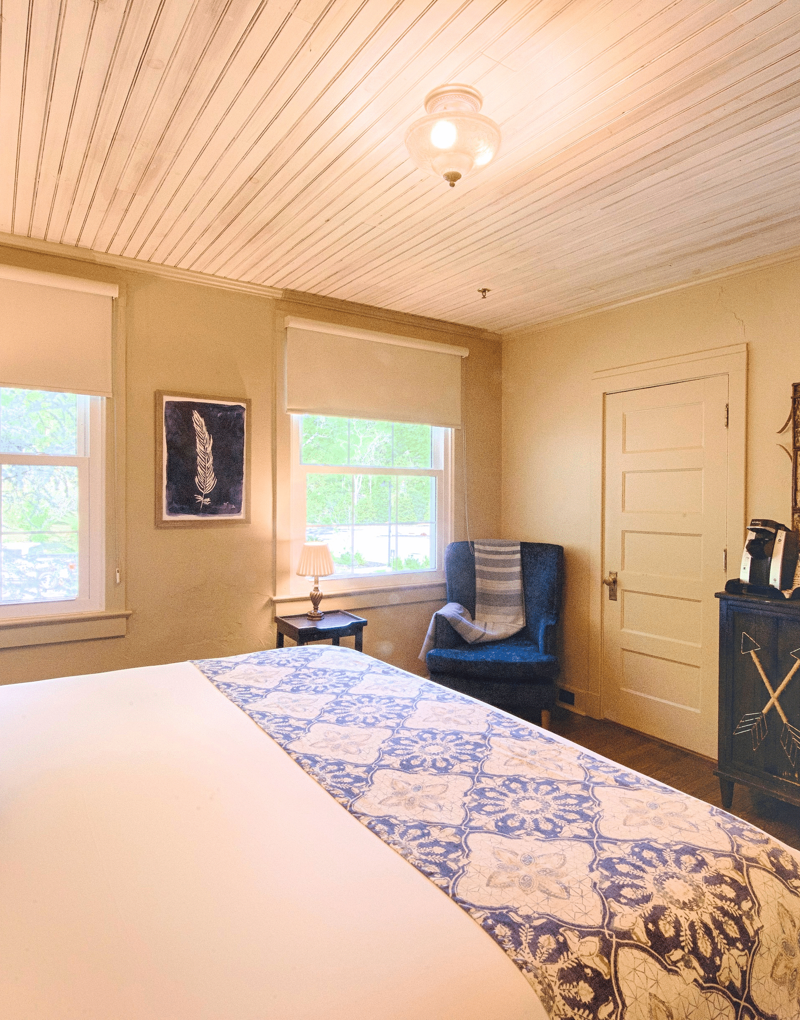 full view image of a cozy bedroom with a comfortable double bed and a wooden cabinet along with a mirror above it - Historic Tapoco Lodge