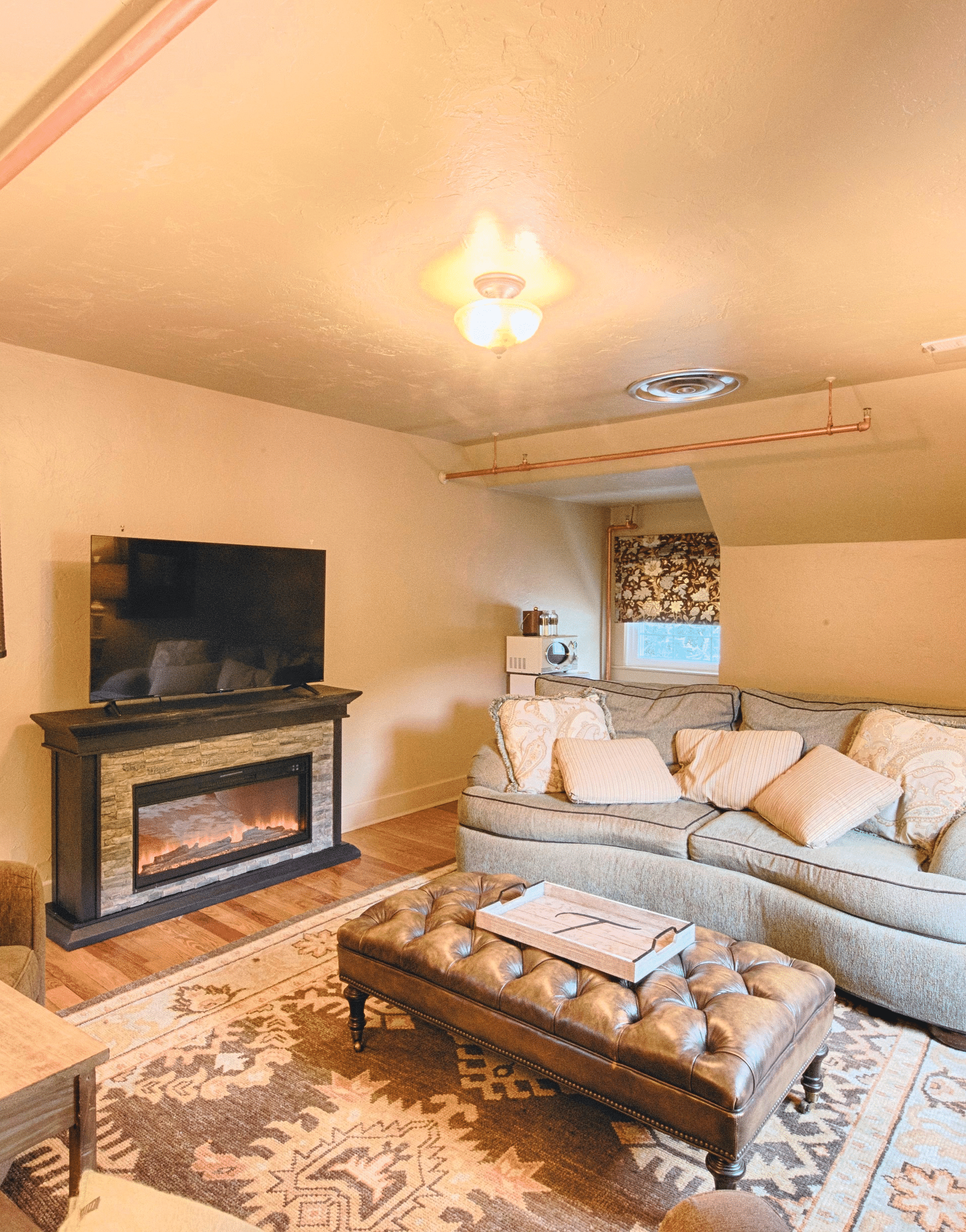 full view image of the living area with a soft couch adorned with a lot of cushions and a beautiful center piece - Historic Tapoco Lodge