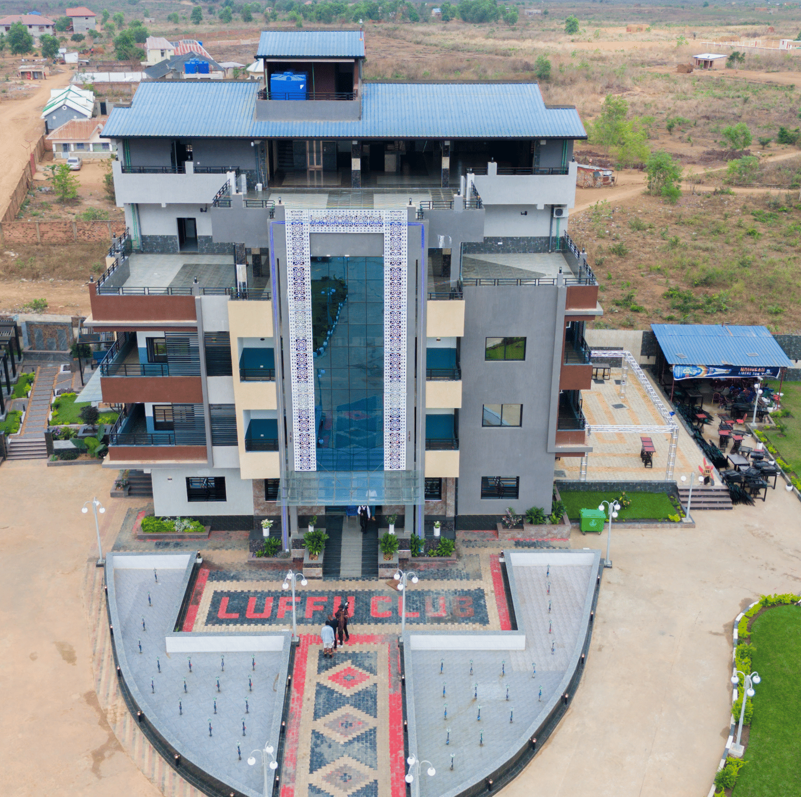 Aerial view of a multi-storey building with a unique facade and patterned forecourt - Luffu Club
