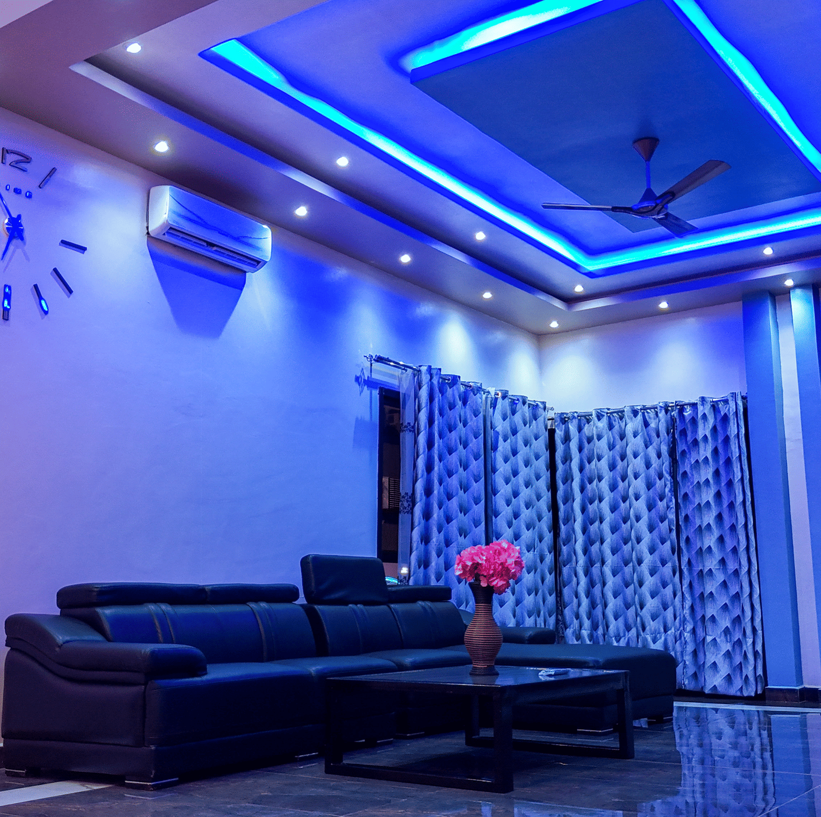 Spacious living room with blue ceiling lights, sofa, and ceiling-to-floor curtains - Luffu Club