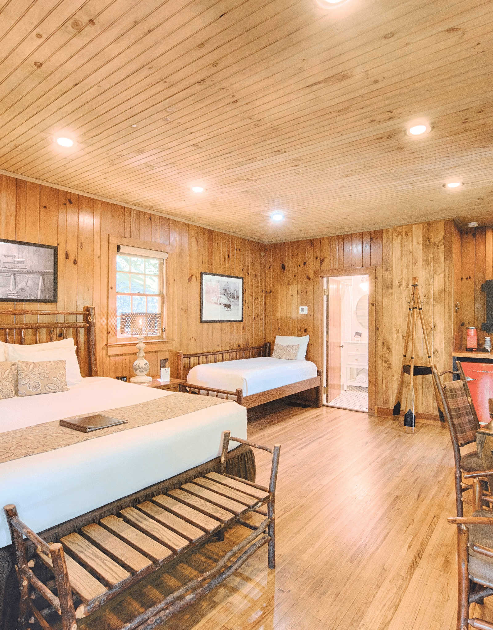 full view image of a the mountain view room with cozy wooden interiors along with a comfortable double bed with a wide landscape portrait above its headboard - Historic Tapoco Lodge