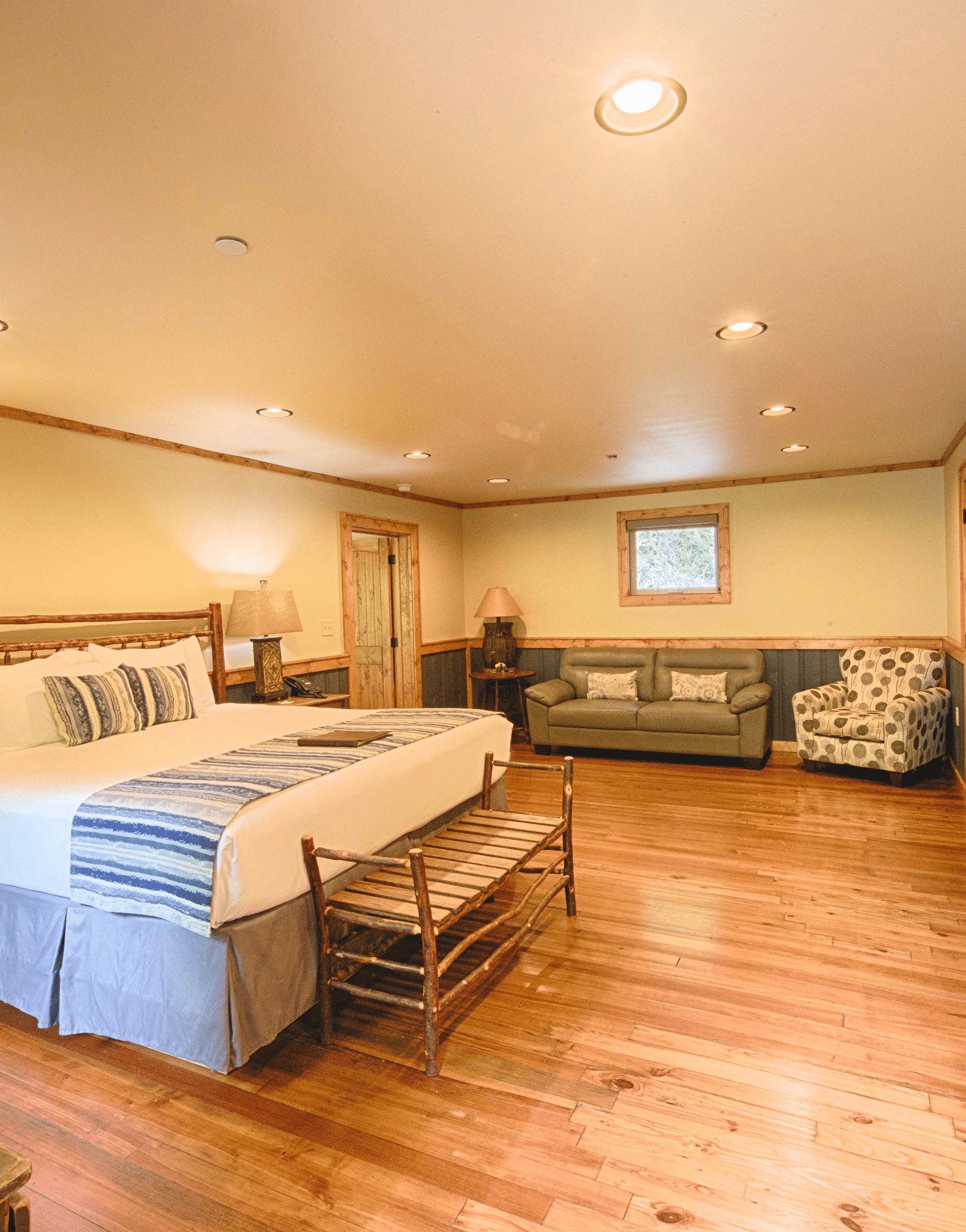 a room featuring a flat screen television wall mounted in front of a double bed along with a plush couch in the corner - Historic Tapoco Lodge