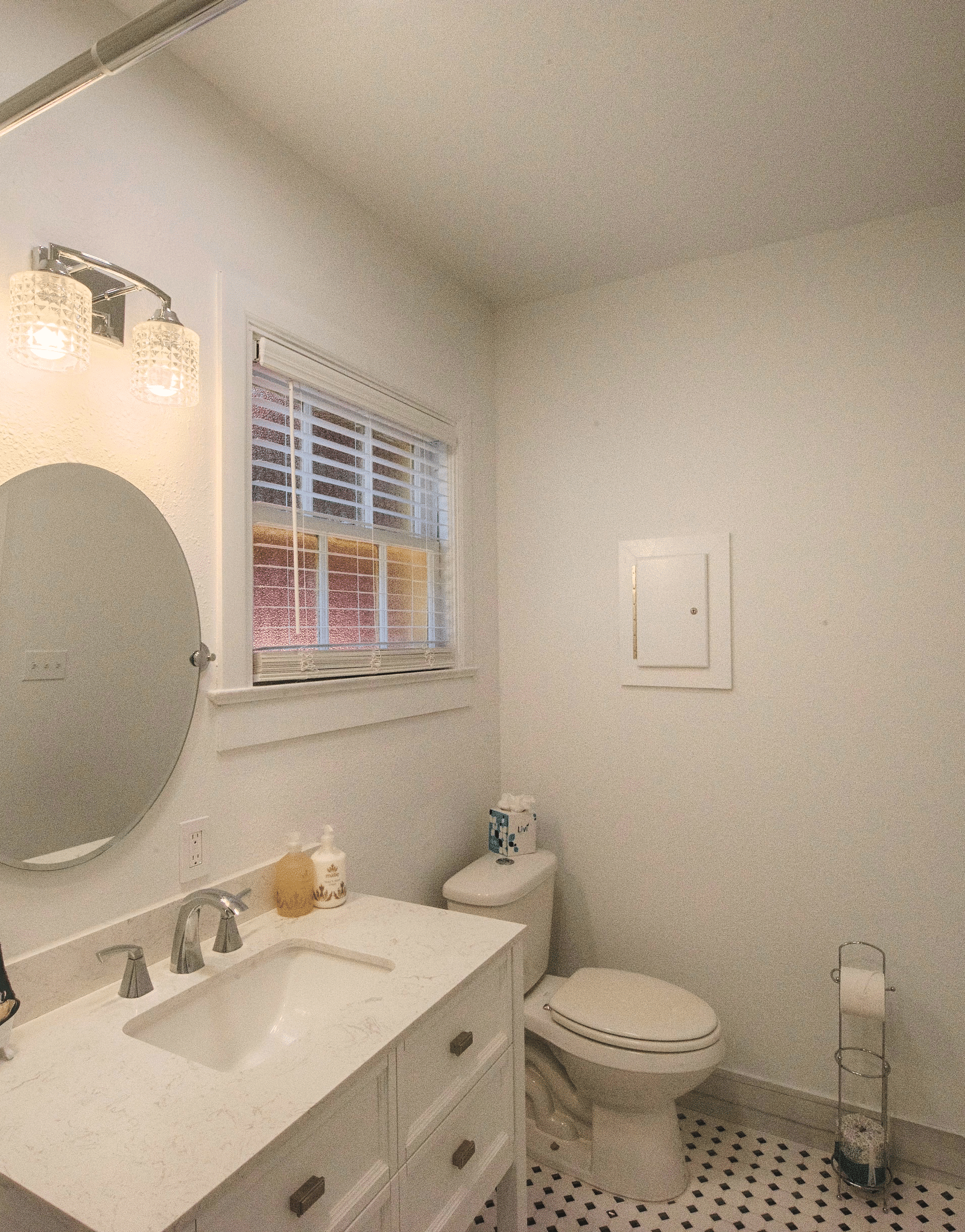 a sleek and compact bathroom with a well equipped vanity area along with a rack with fresh towels stowed on it - Historic Tapoco Lodge