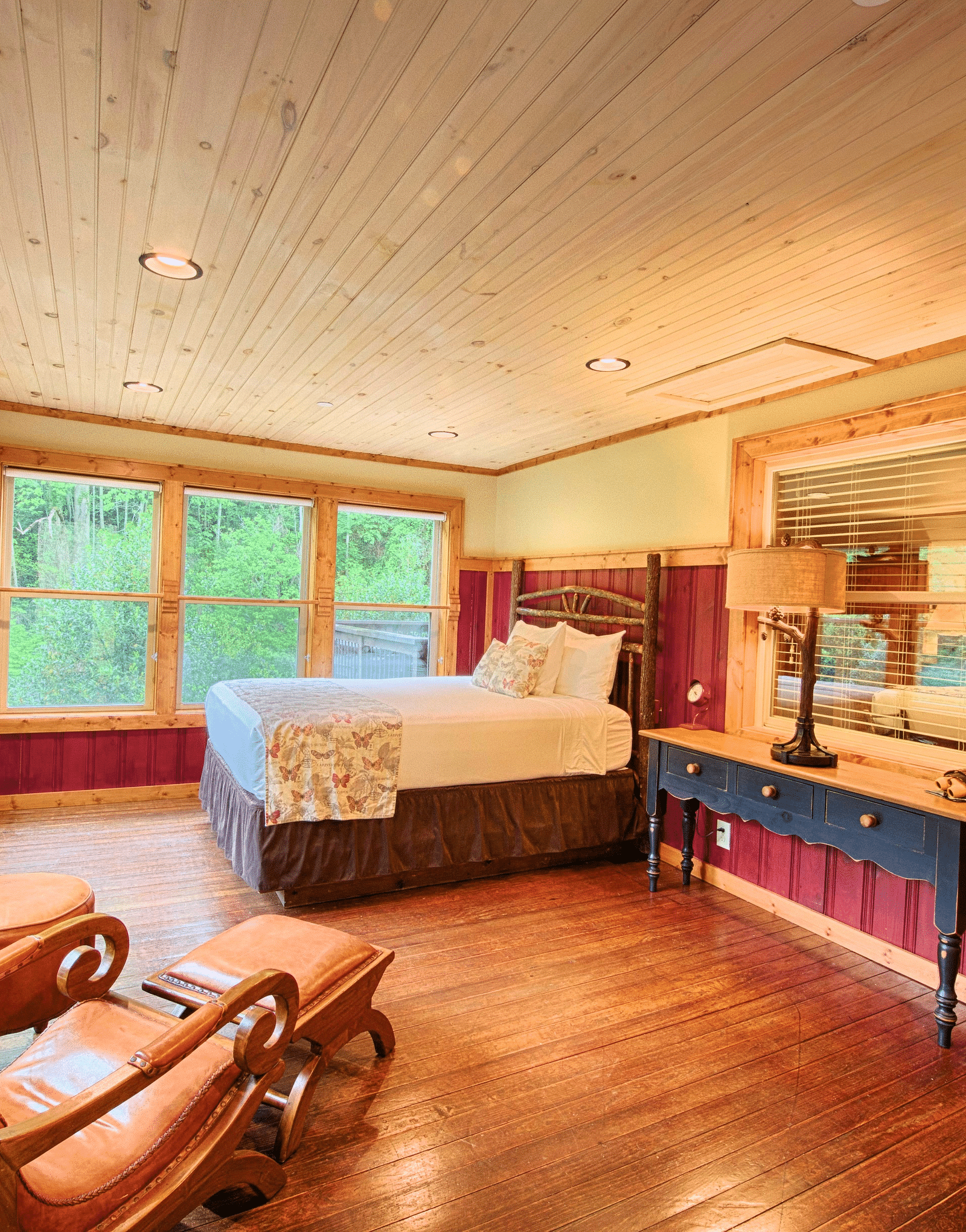 side view image of a bedroom featuring a double bed along with a cushioned armchair and a huge mirror besides it - Historic Tapoco Lodge