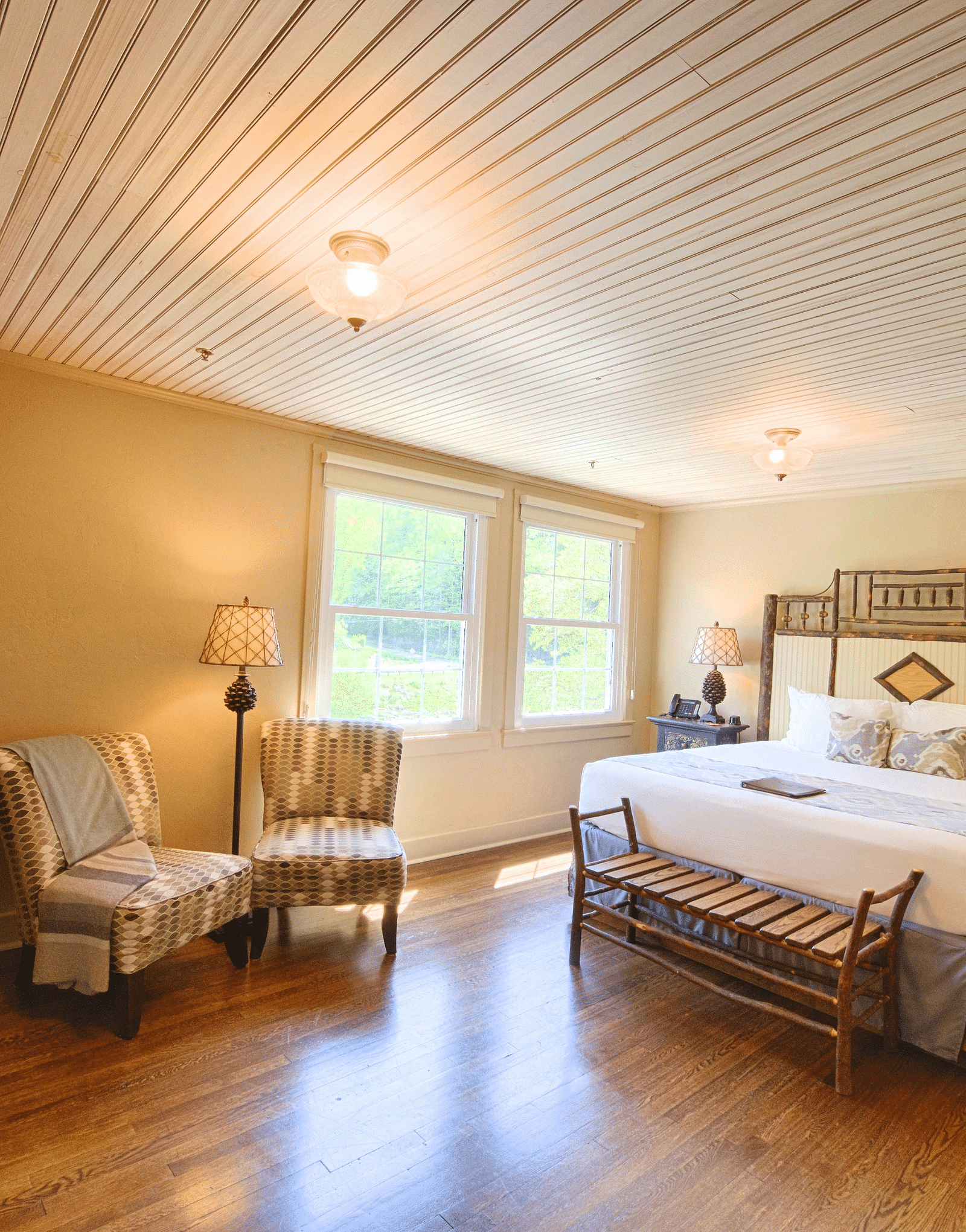 full view image of a bedroom with a plush double bed with a beautiful headboard and a bathrobe hanging on the bathroom door - Historic Tapoco Lodge
