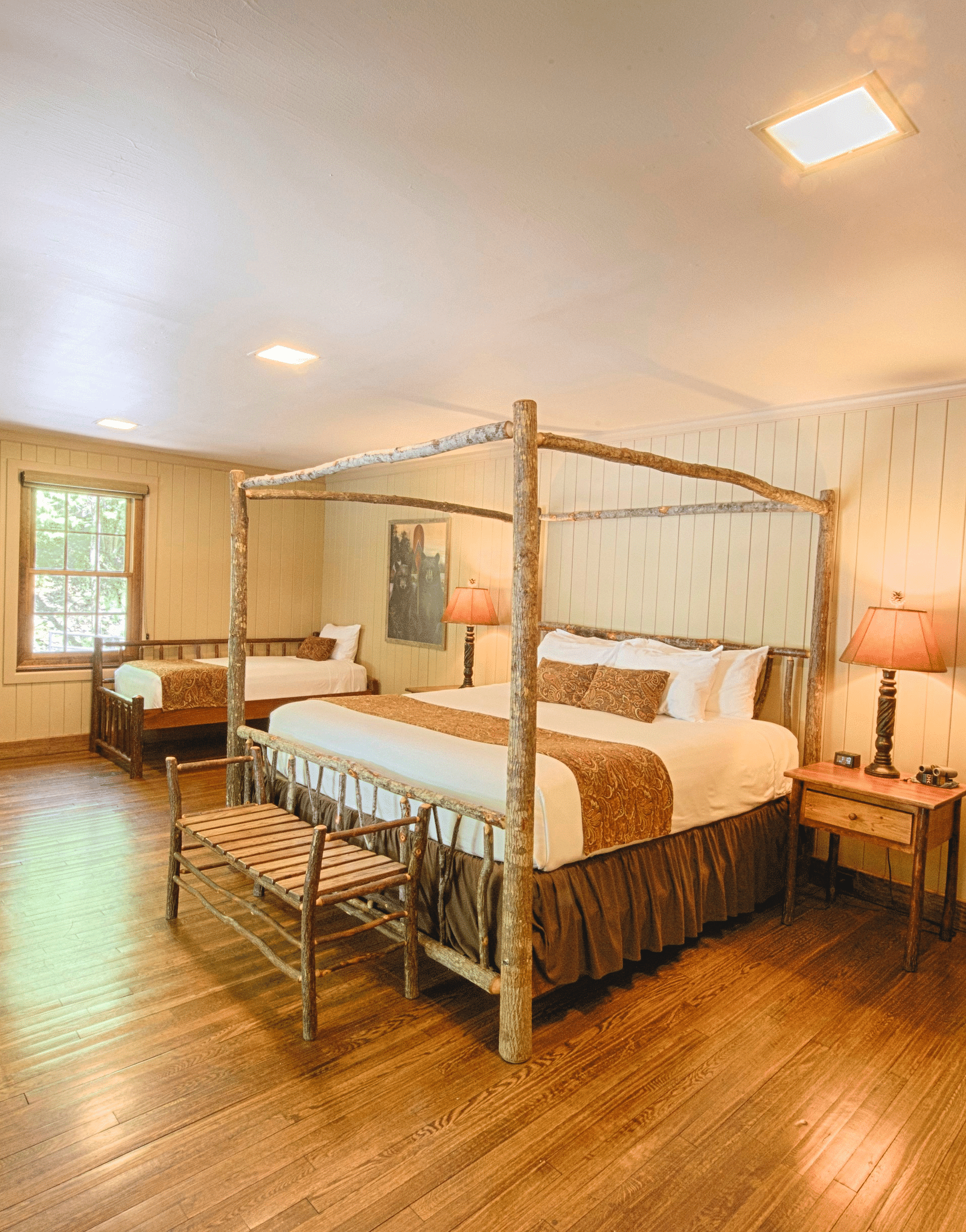 corner view image of a room with a double bed surrounded by four wooden pillars bed side tables - Historic Tapoco Lodge