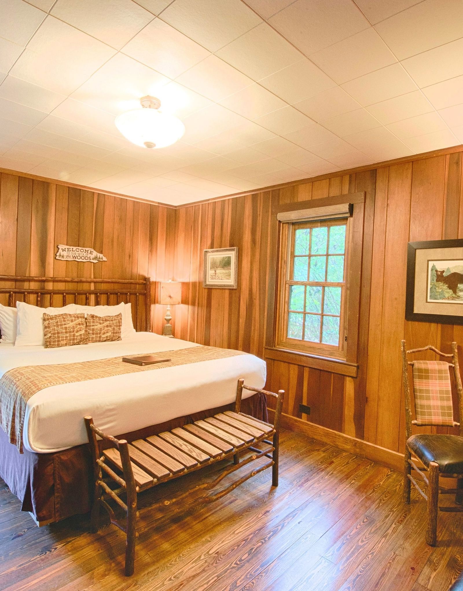 full view image of the a bedroom with a couple bed along with a small seating are in front of the bed - Historic Tapoco Lodge