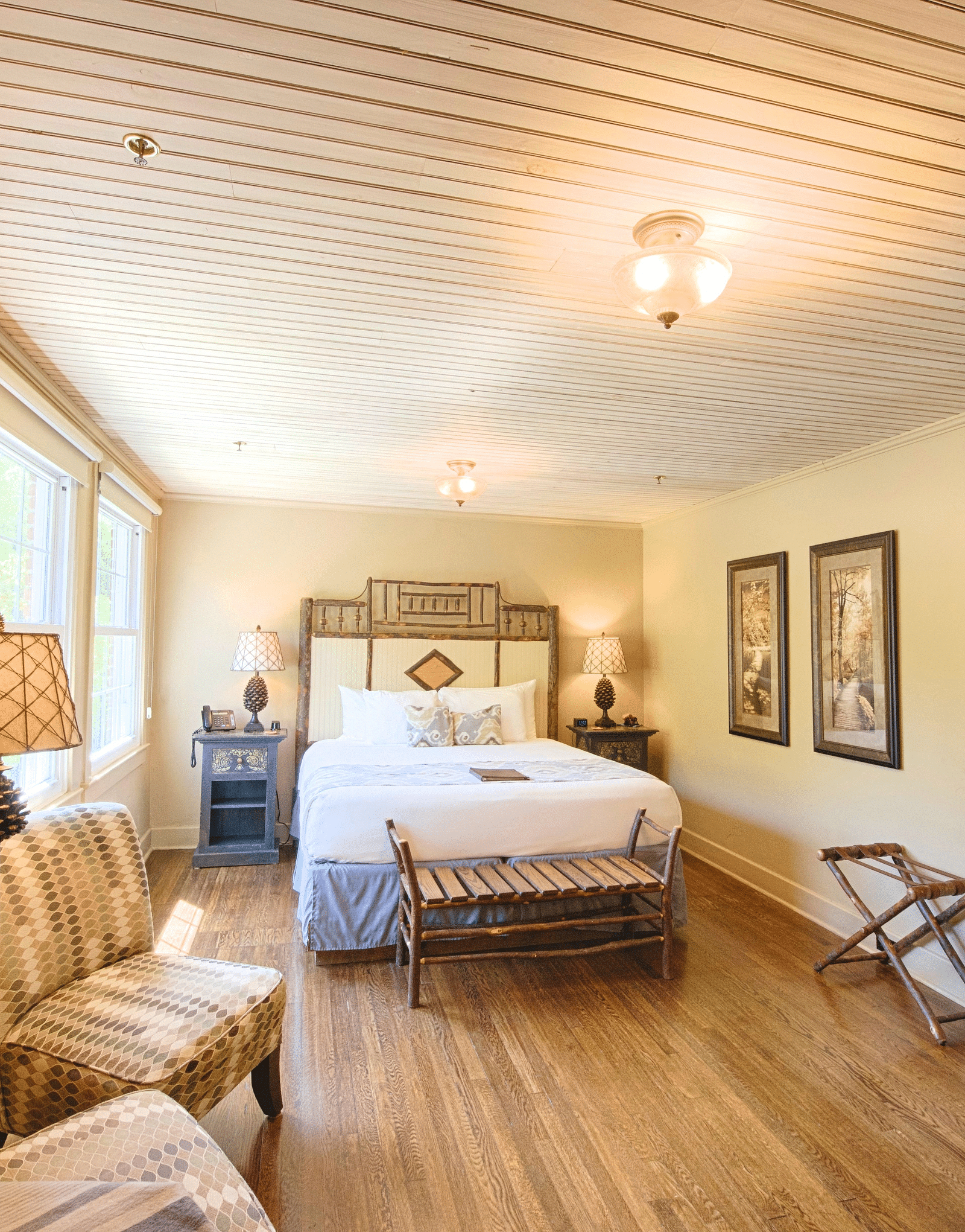full view image of a bedroom with modern furnishings featuring a double bed along with two cushioned armchairs - Historic Tapoco Lodge
