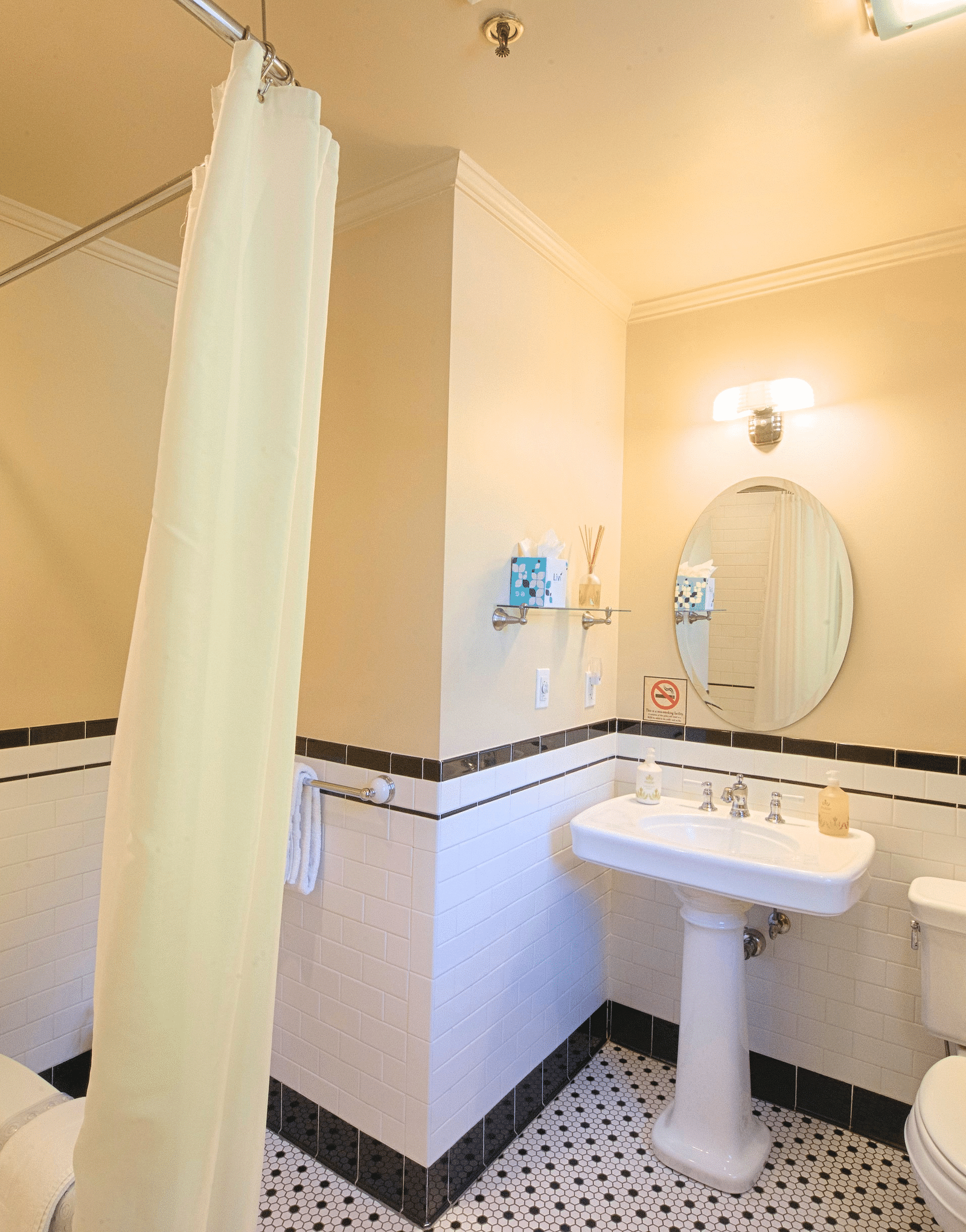 a bathroom featuring a commode along with wash basin with a circular mirror above it - Historic Tapoco Lodge