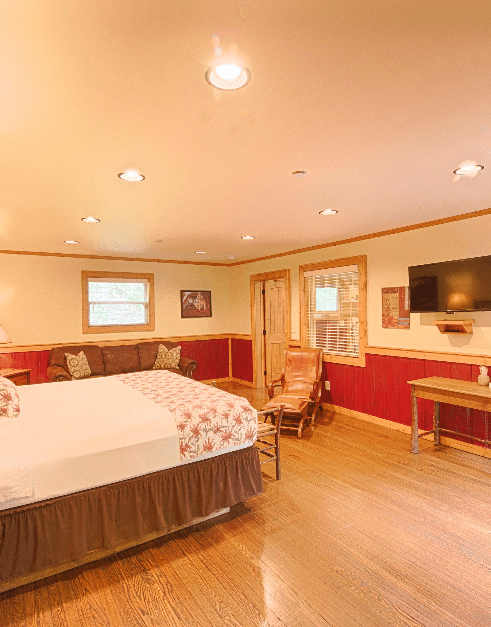 corner view image of a room featuring a double bed placed right opposite to a flat screen wall mounted television - Historic Tapoco Lodge