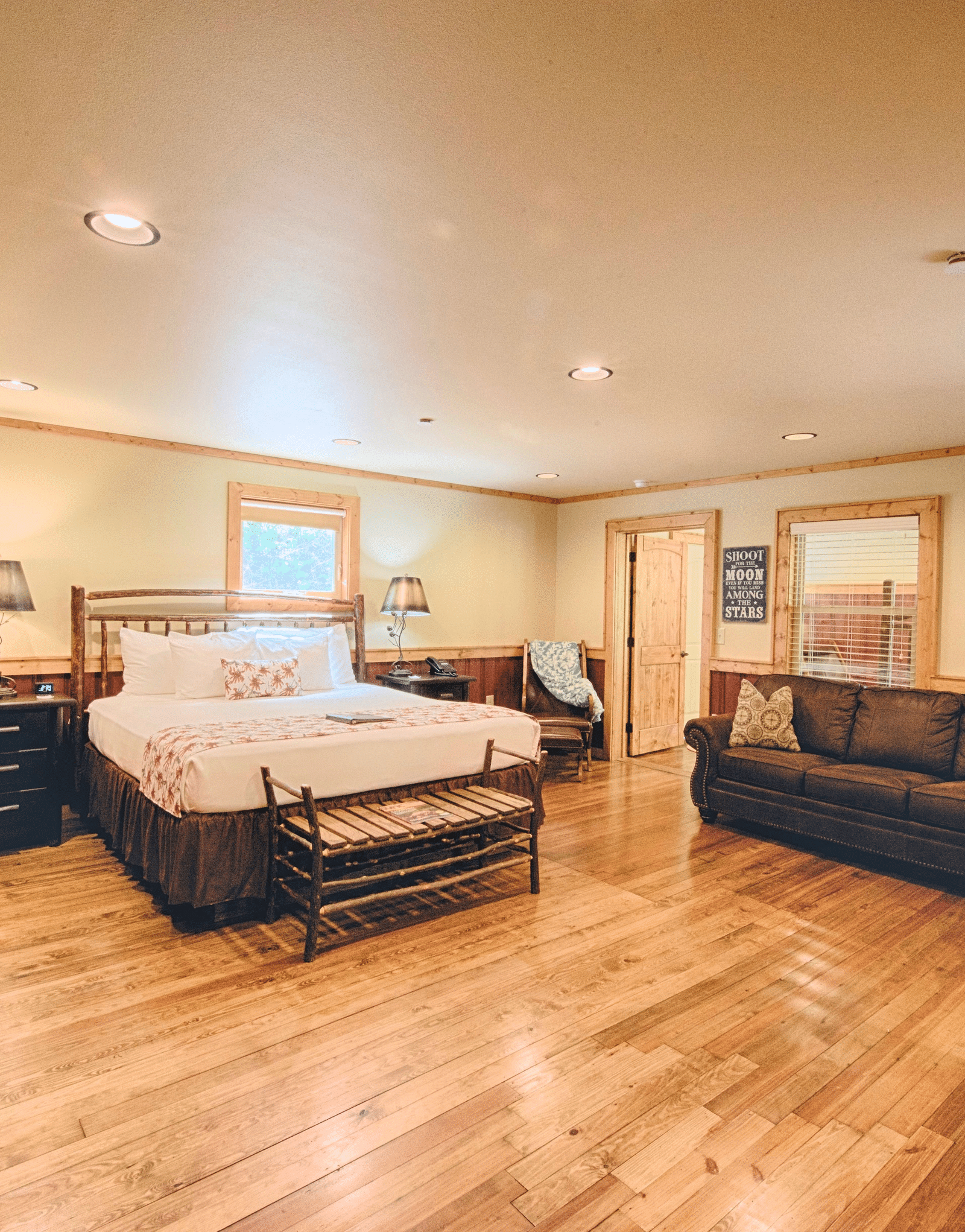 full view image of a room with a double bed along with a common seating area opposite to it - Historic Tapoco Lodge