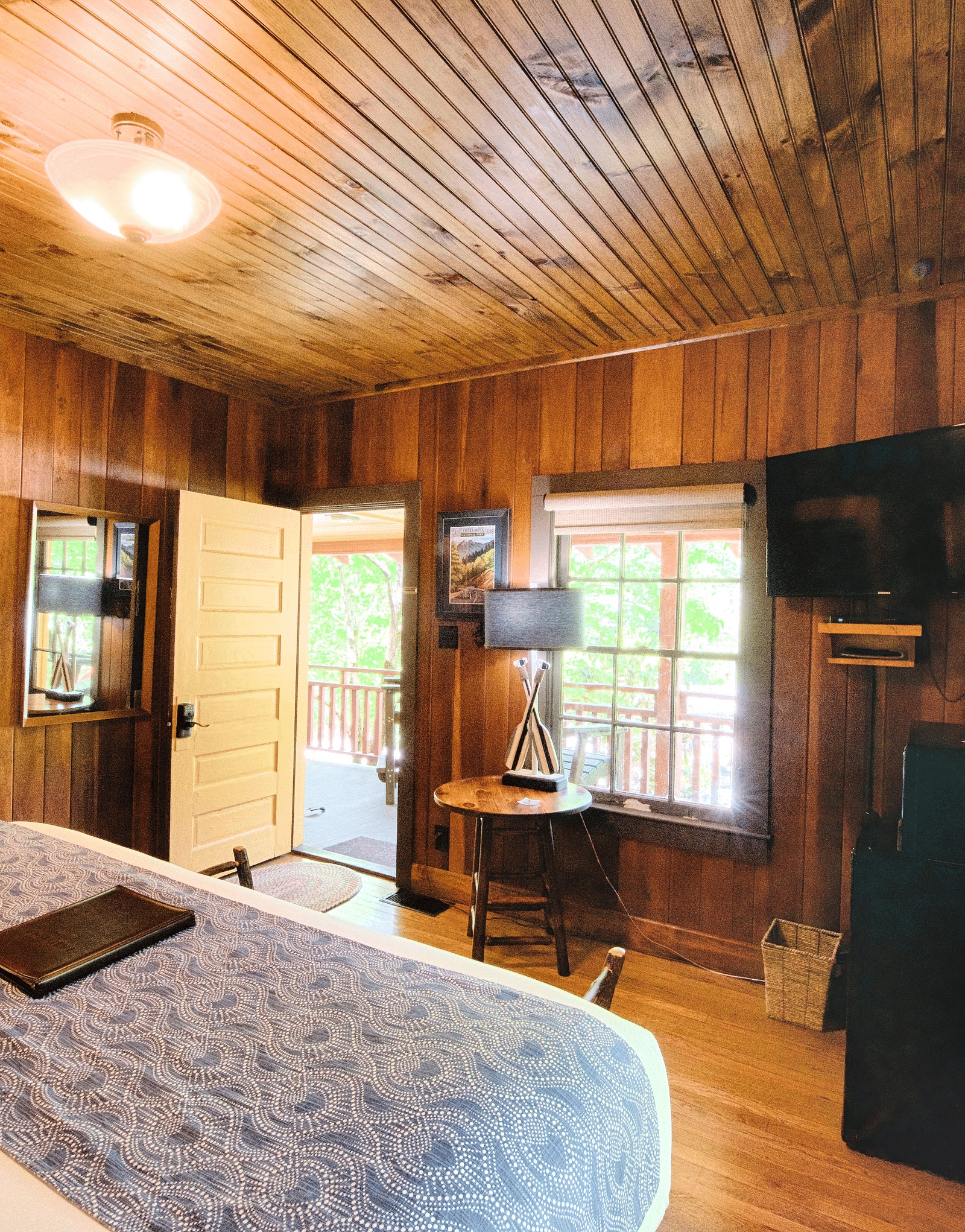 a wooden cabin overlooking a double bed with wooden panel ceiling above it - Historic Tapoco Lodge